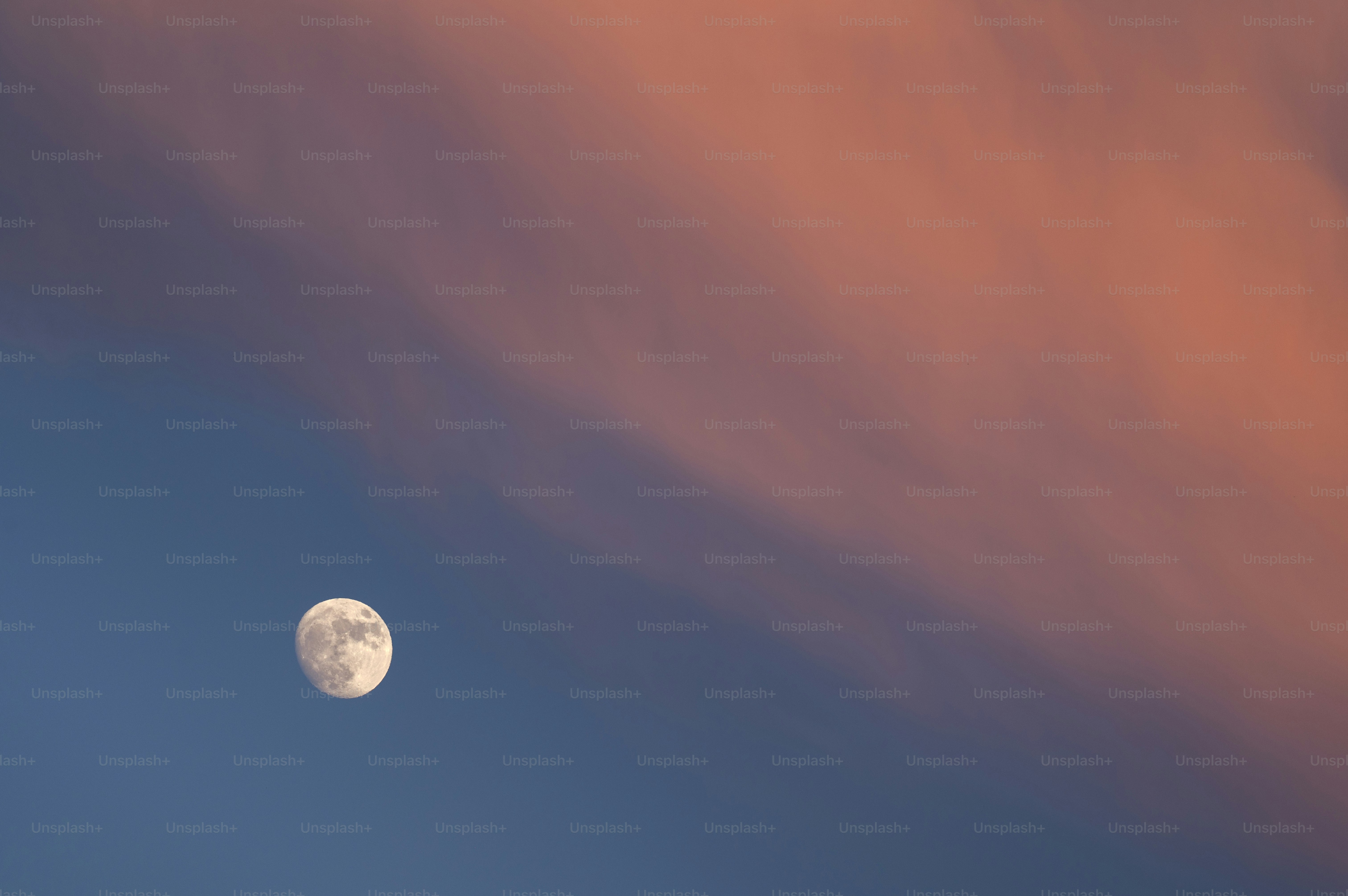 Full moon in a dusky sky with pink clouds