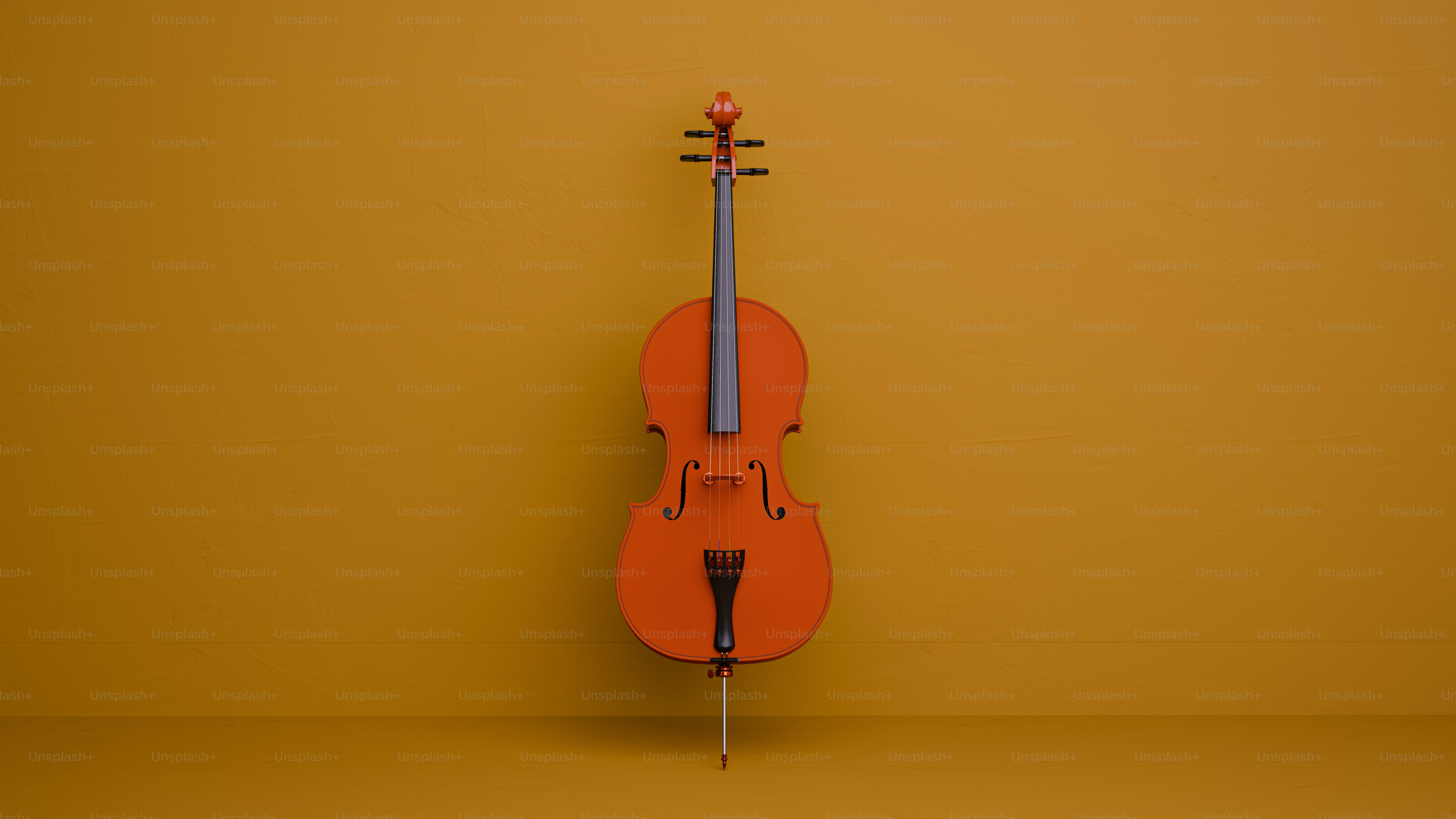 オレンジ色のチェロが黄色い壁に立てかけられています。