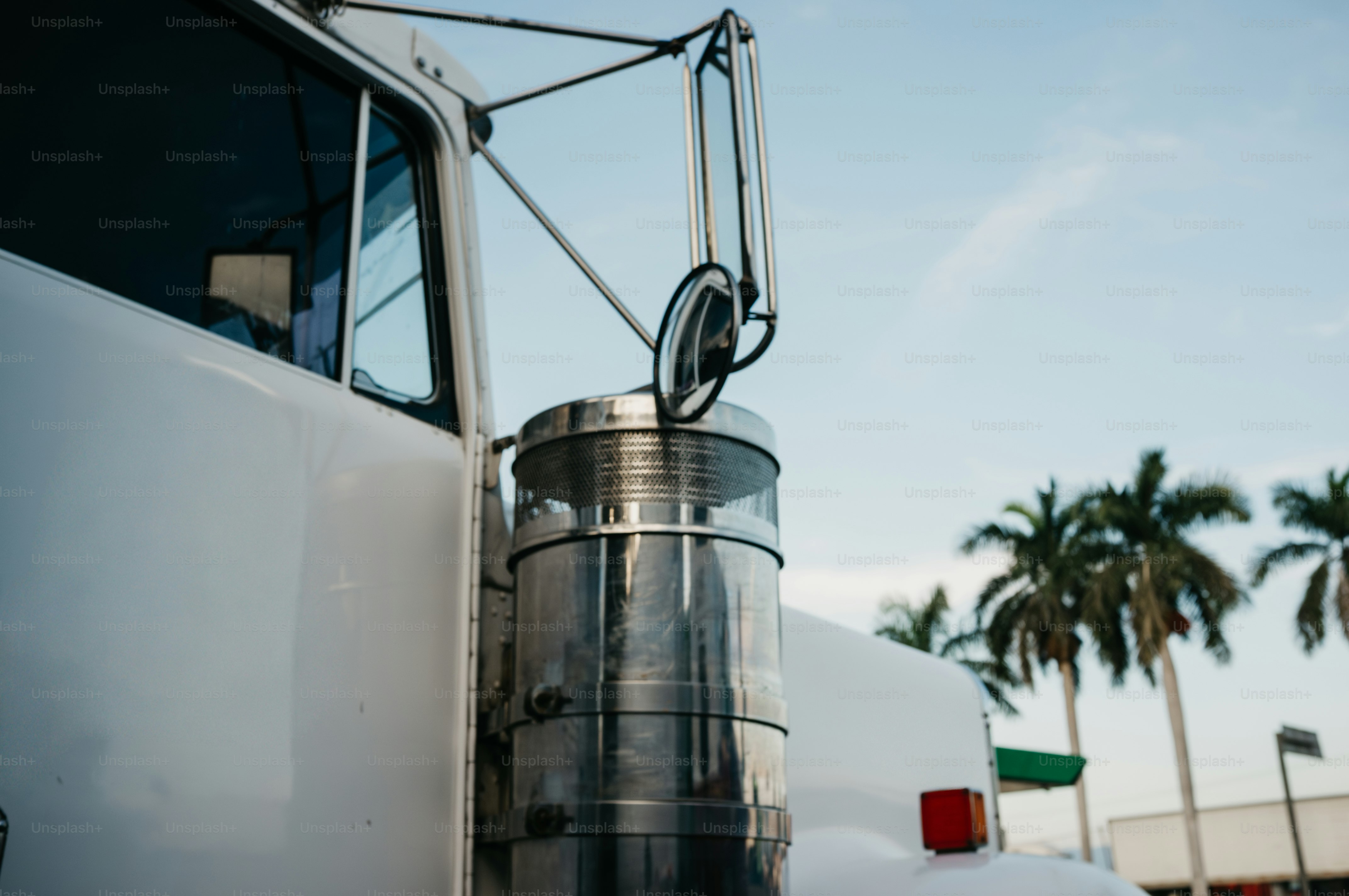White semi-truck with chrome exhaust pipe and palm trees