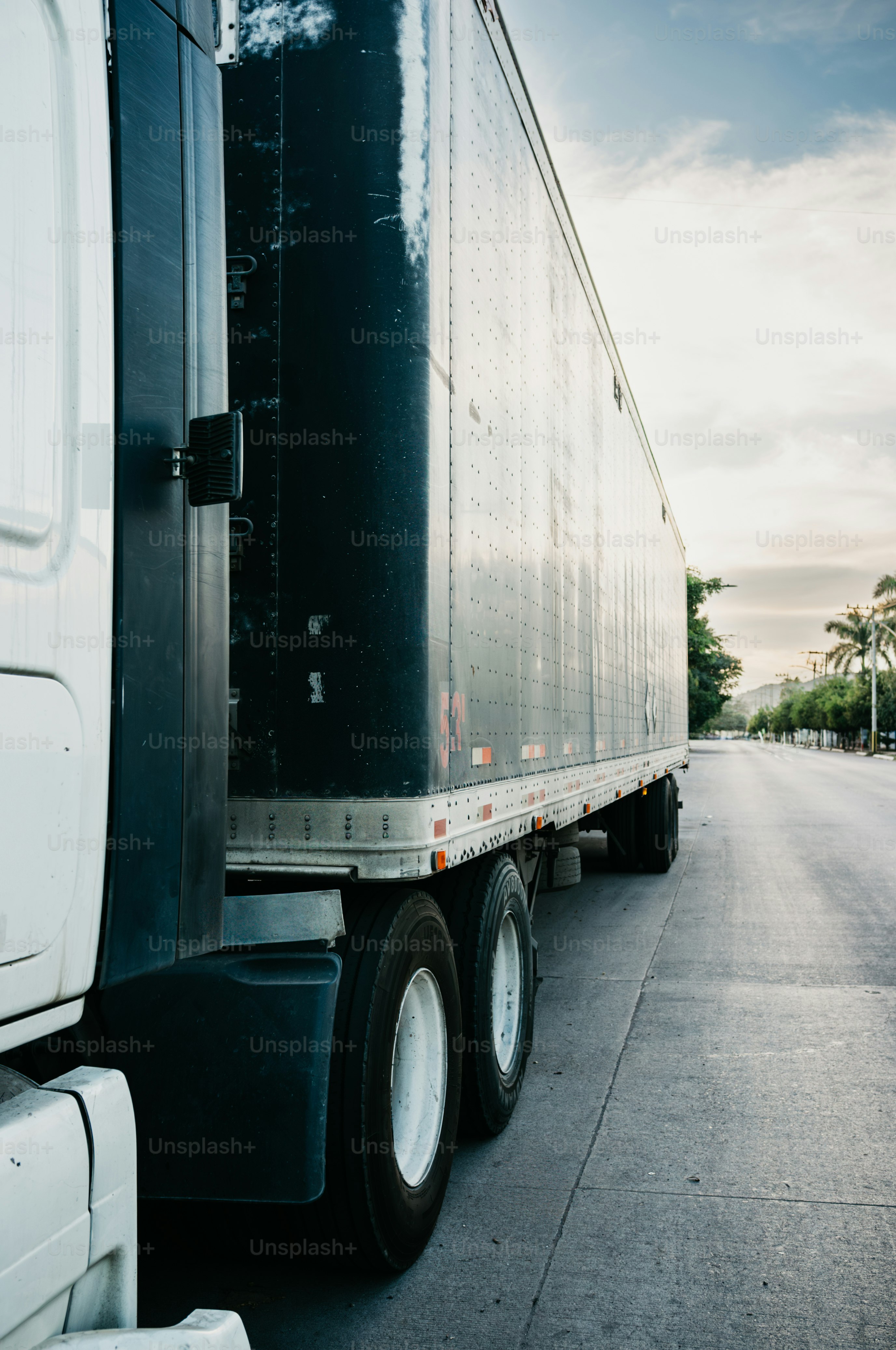 A white semi-truck parked on the side of the road.