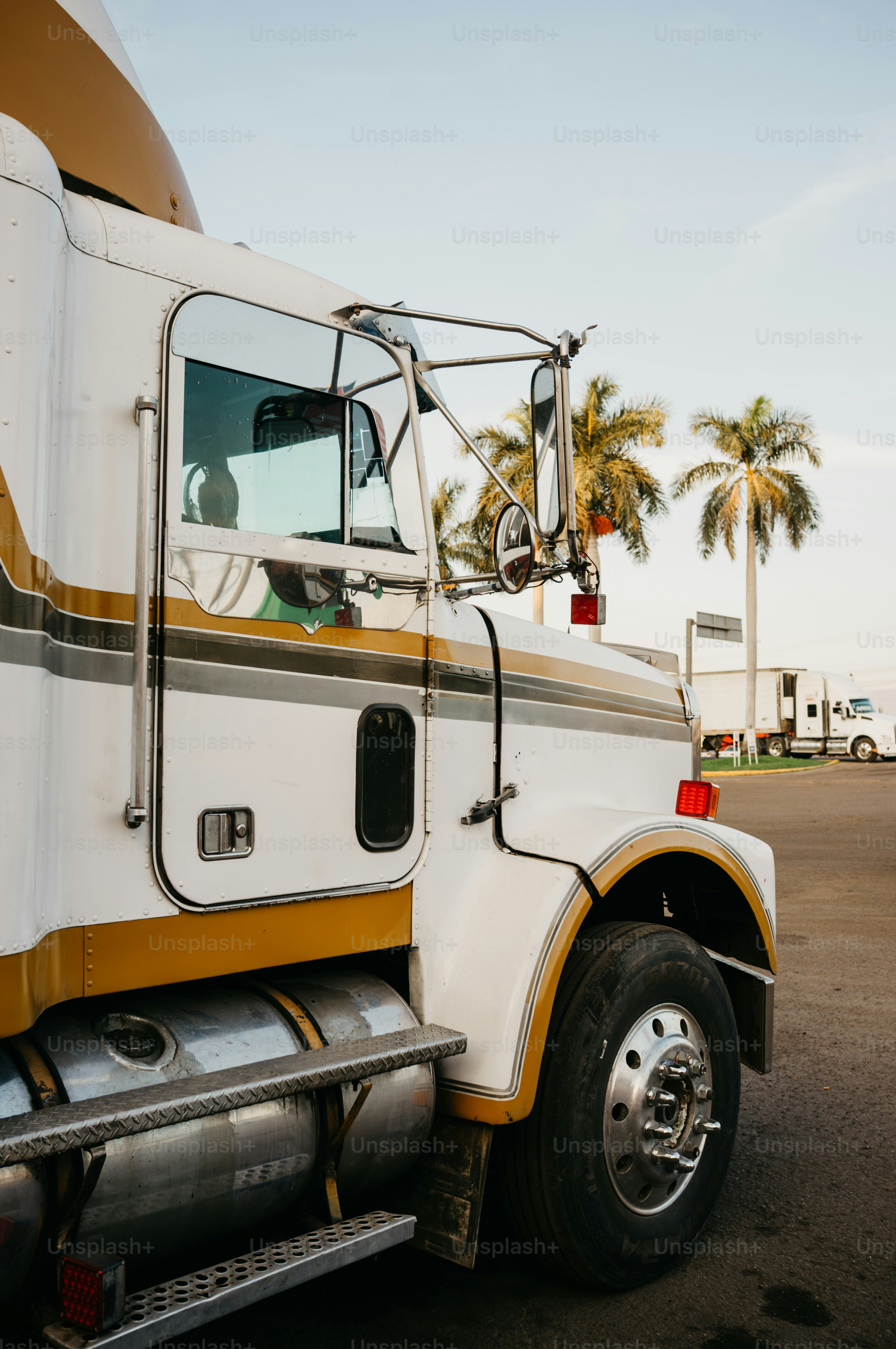 White semi-truck with gold stripes parked outdoors.