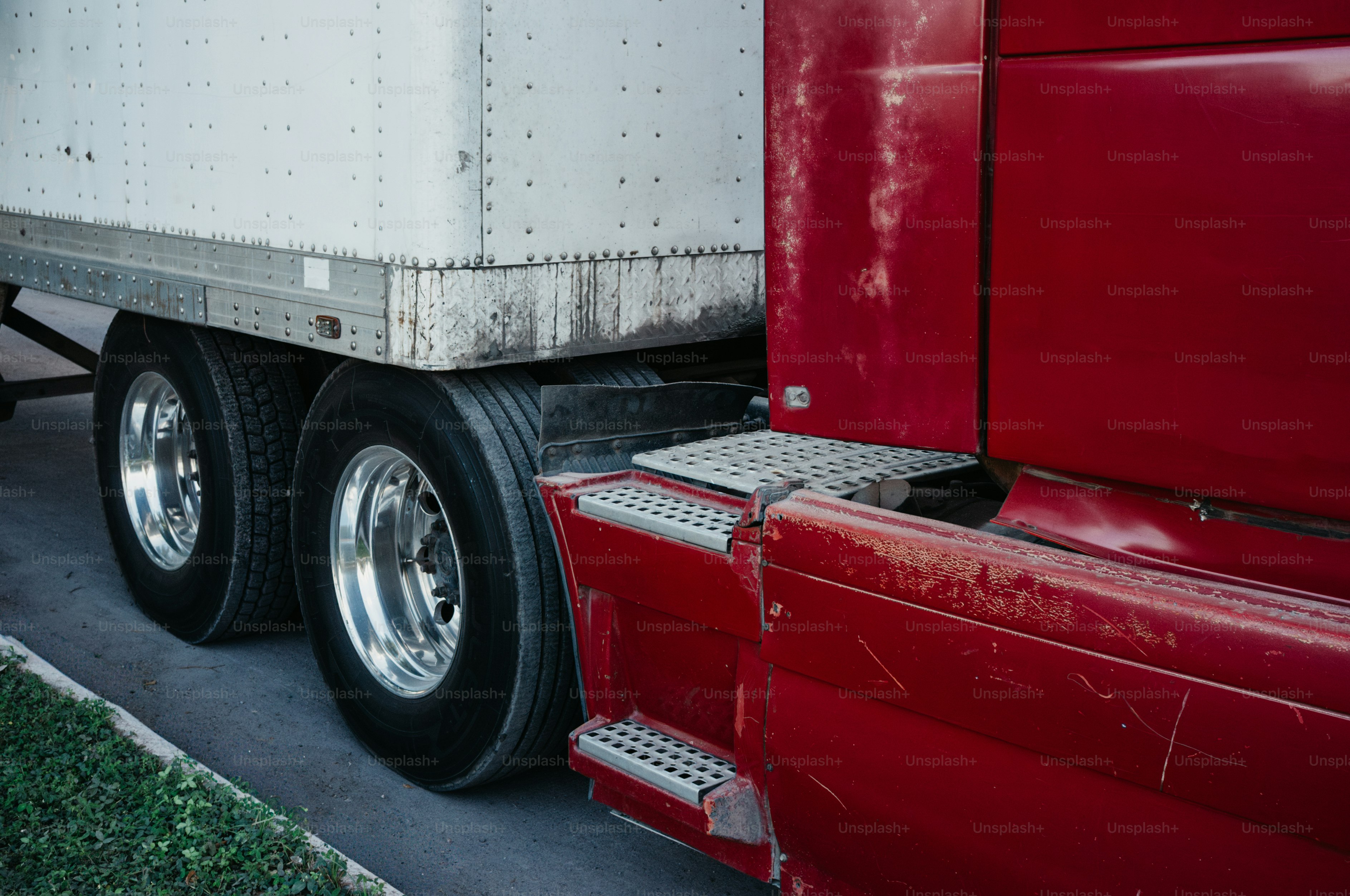 Red semi-truck with a white trailer attached trailer.