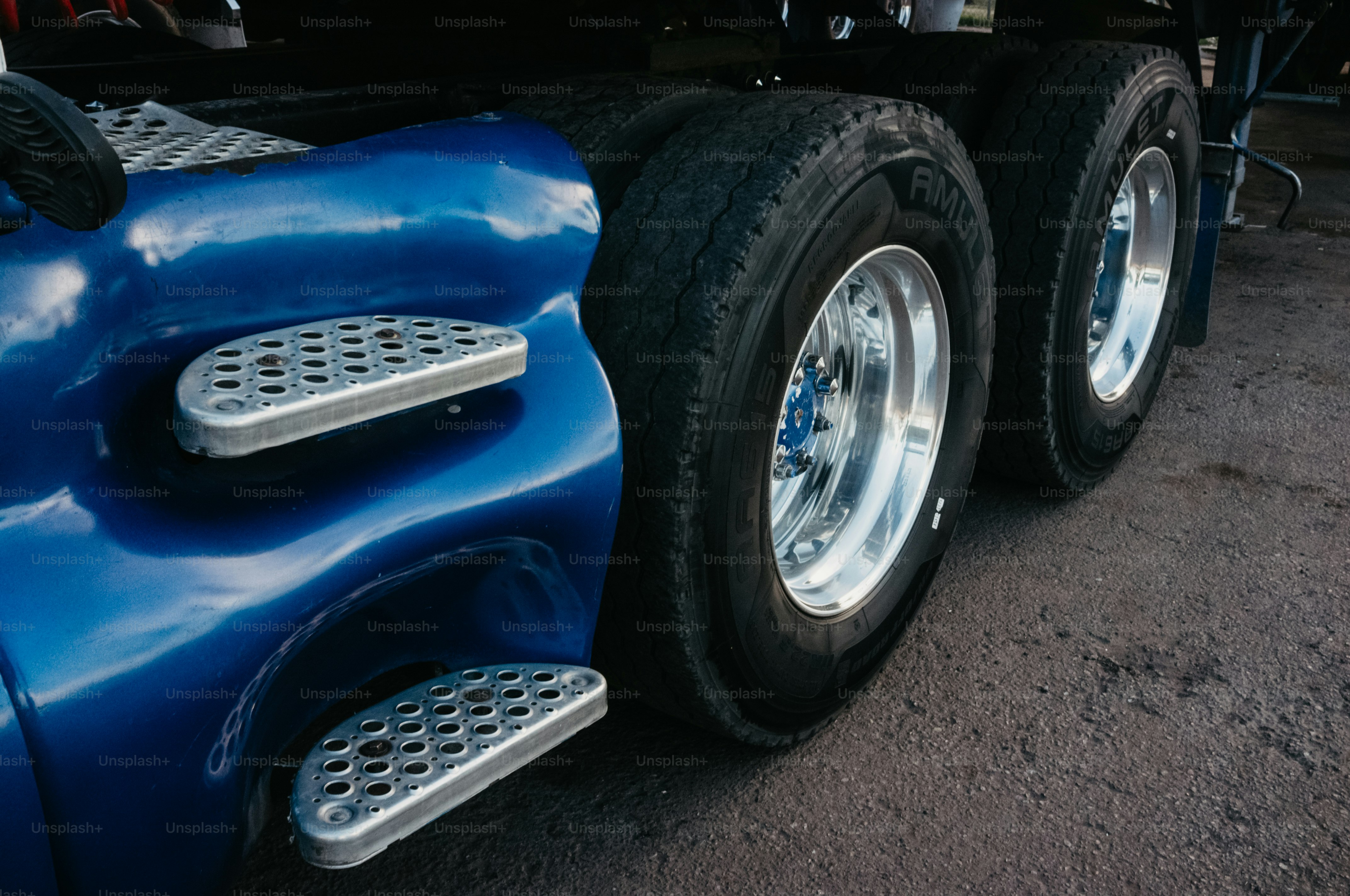 Close-up of blue semi-truck dual wheels and steps