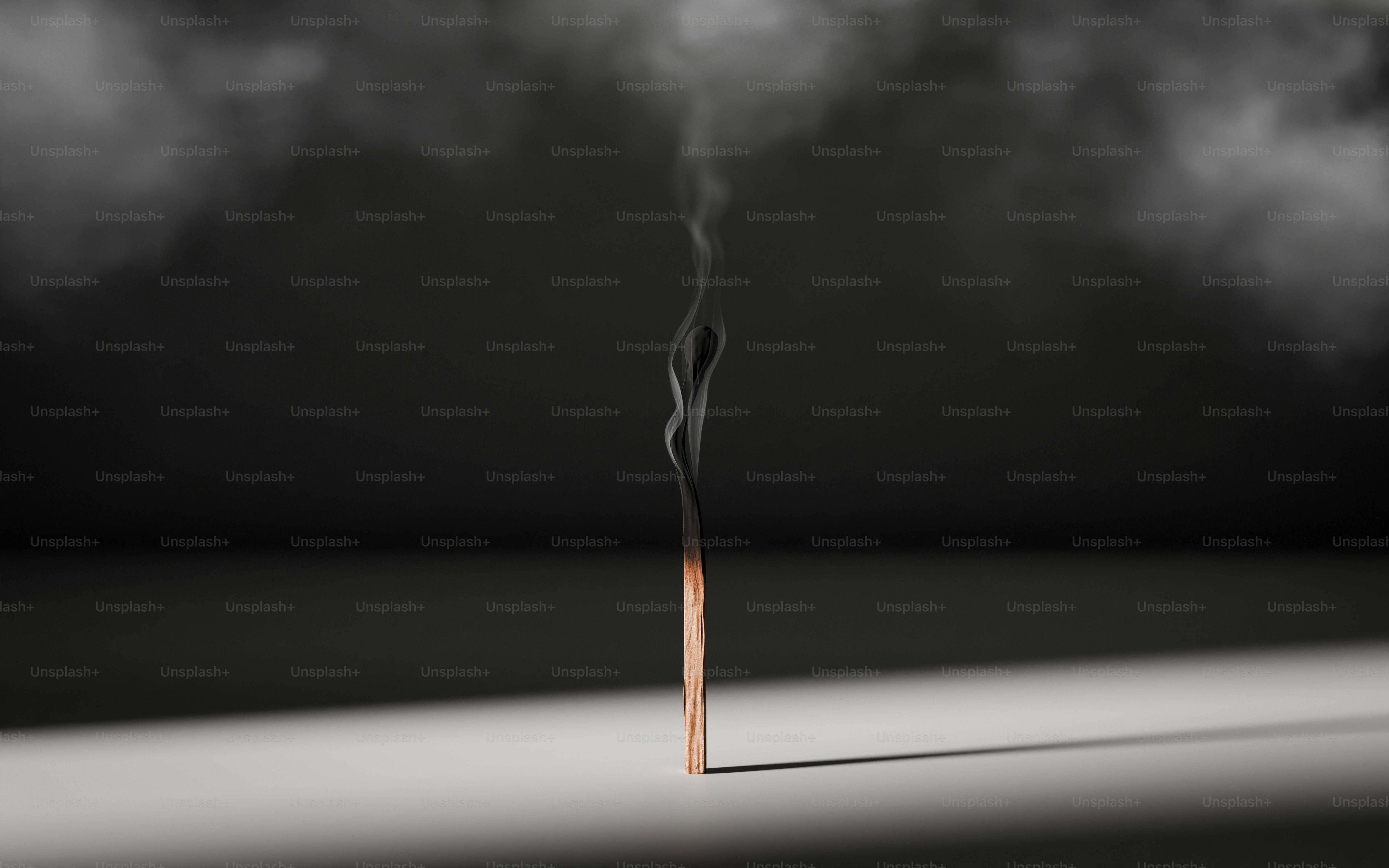 A single matchstick smoking against a dark background.