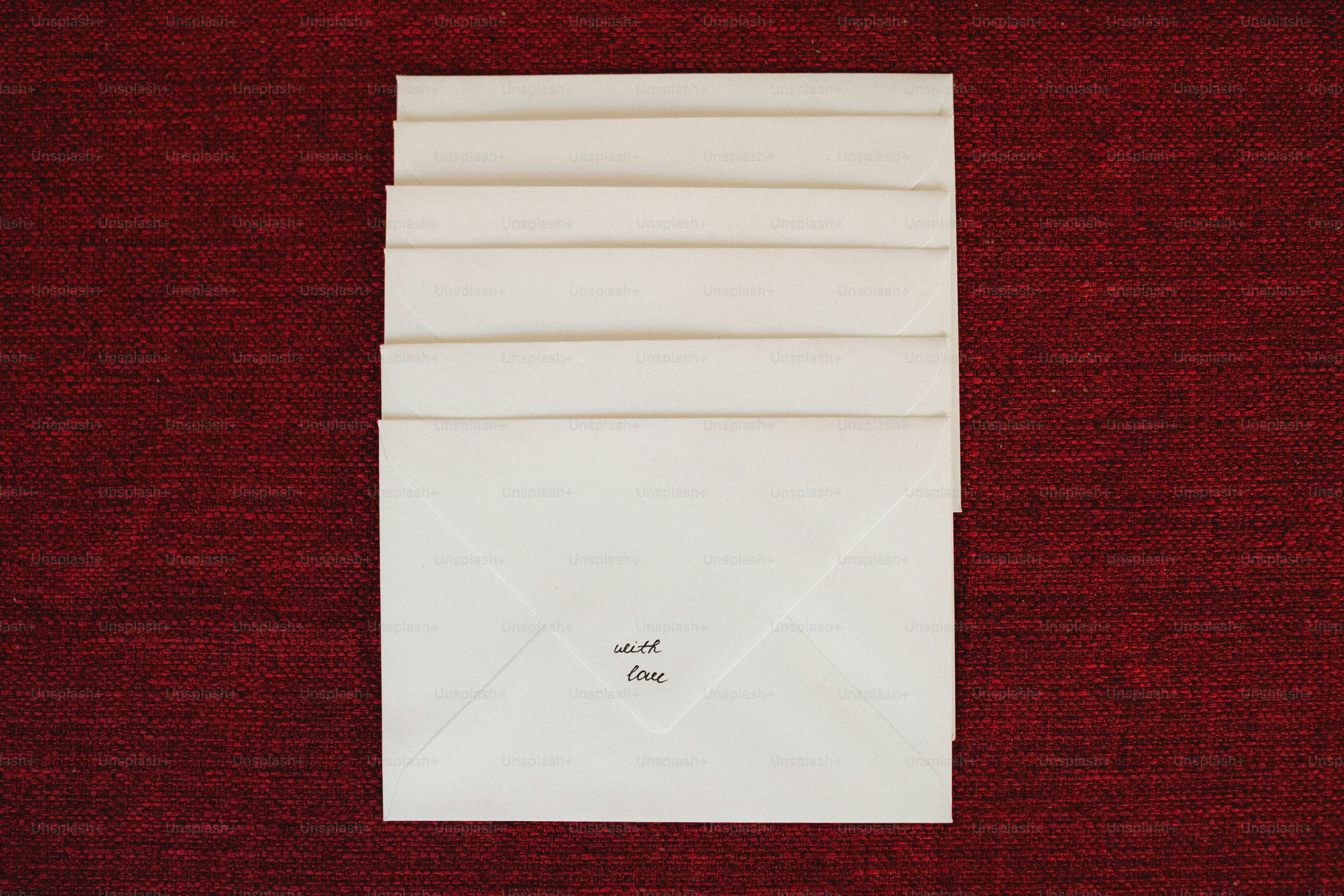 Stack of white envelopes on a red textured surface
