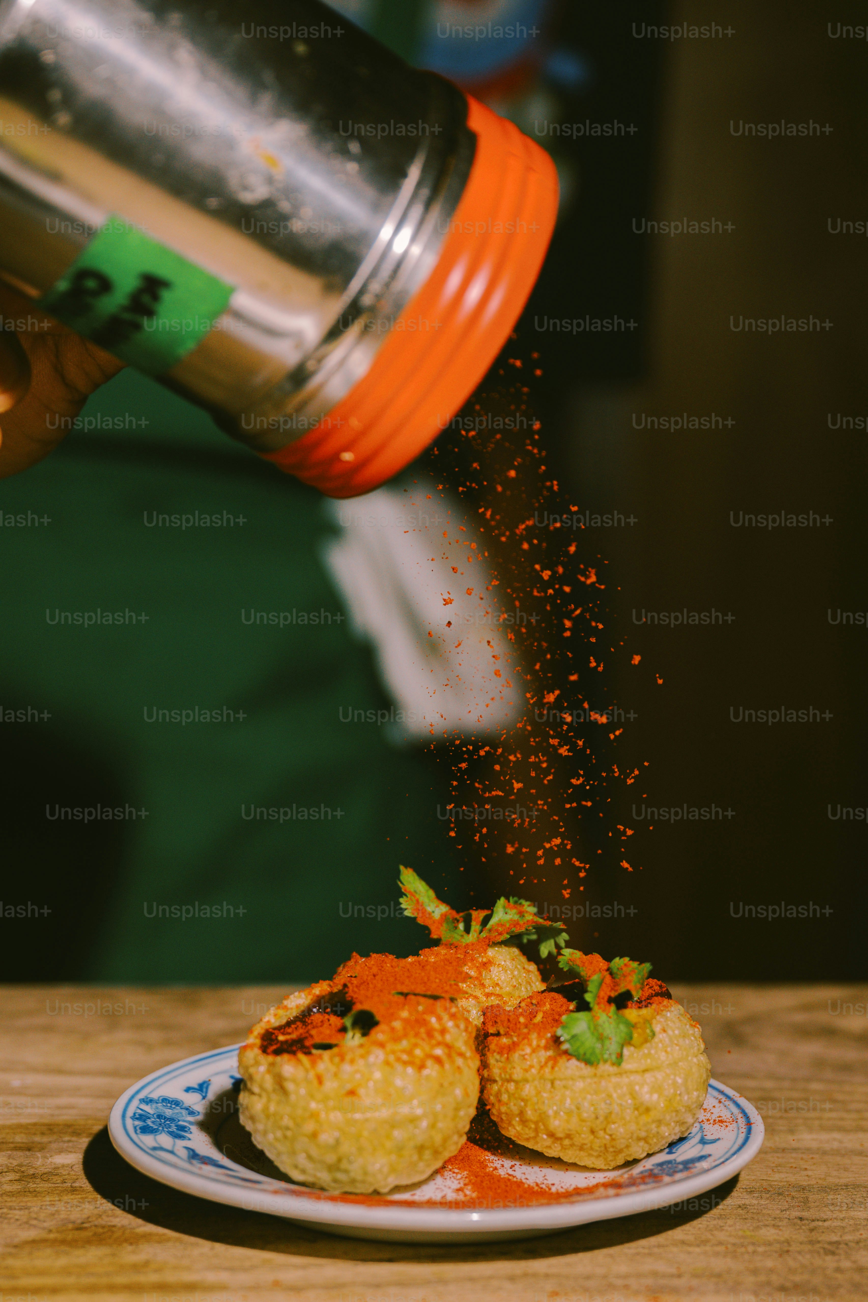 Seasoning being sprinkled onto small stuffed pastries.