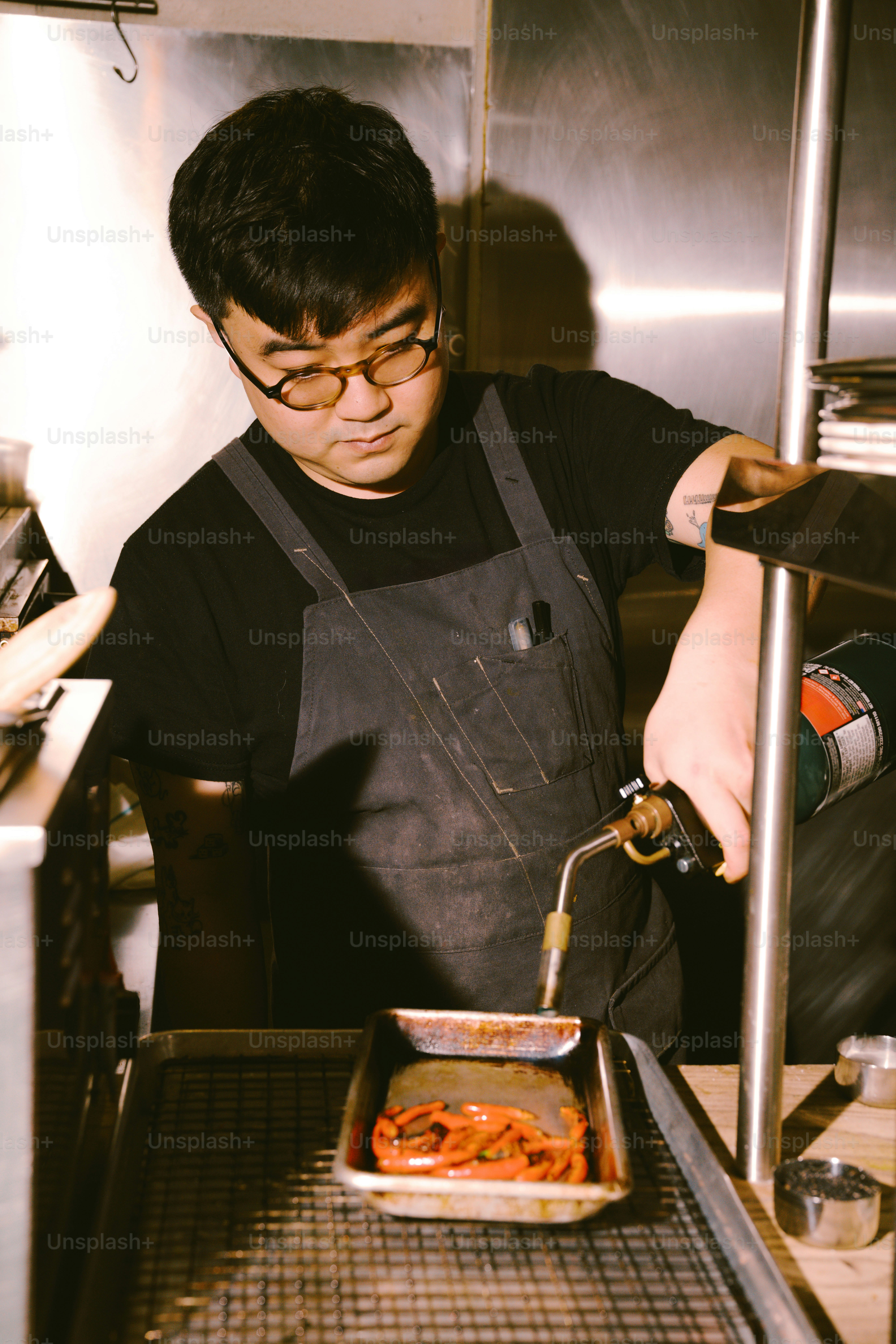 Chef using a torch on food in a pan