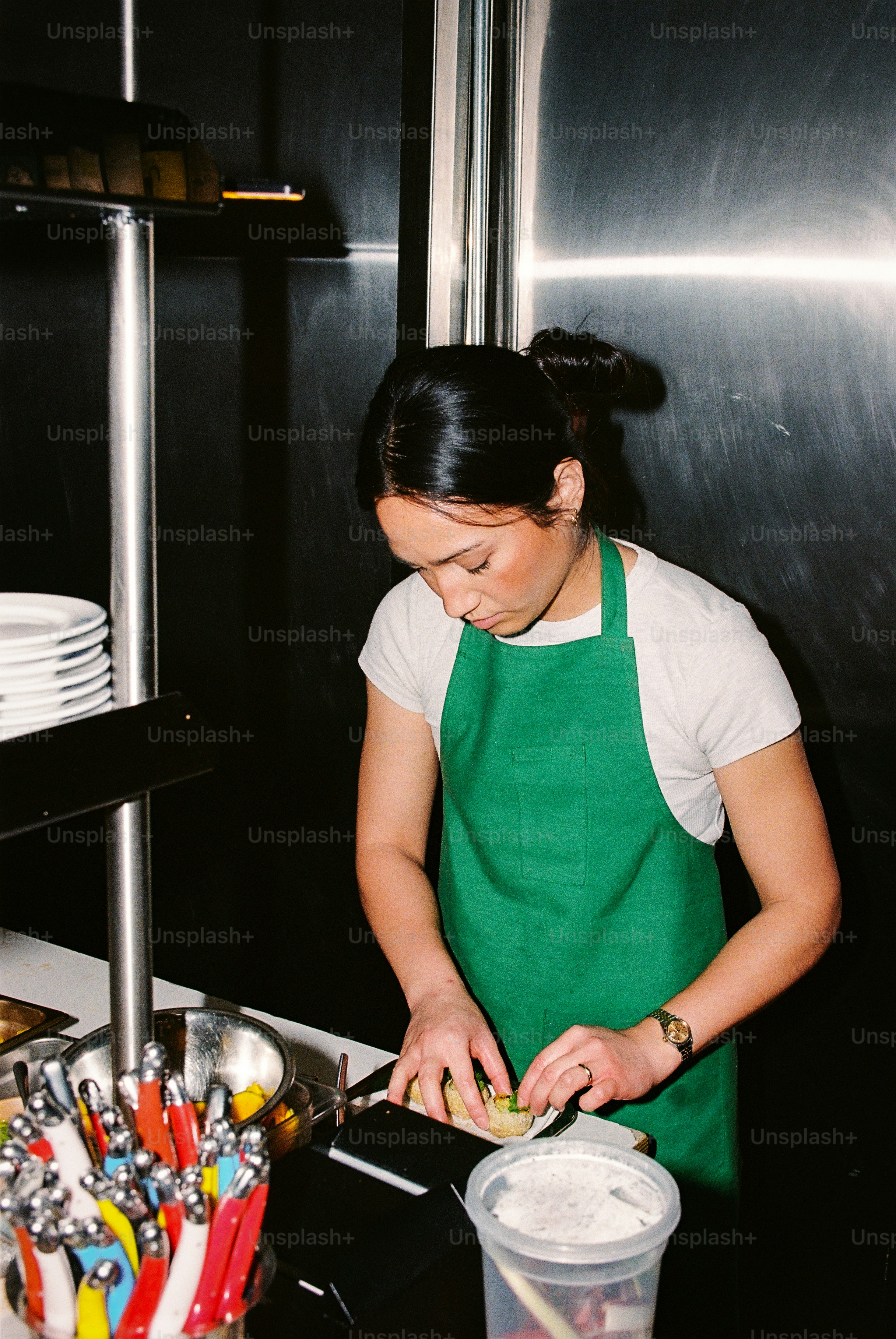 A woman in a green apron preparing food.