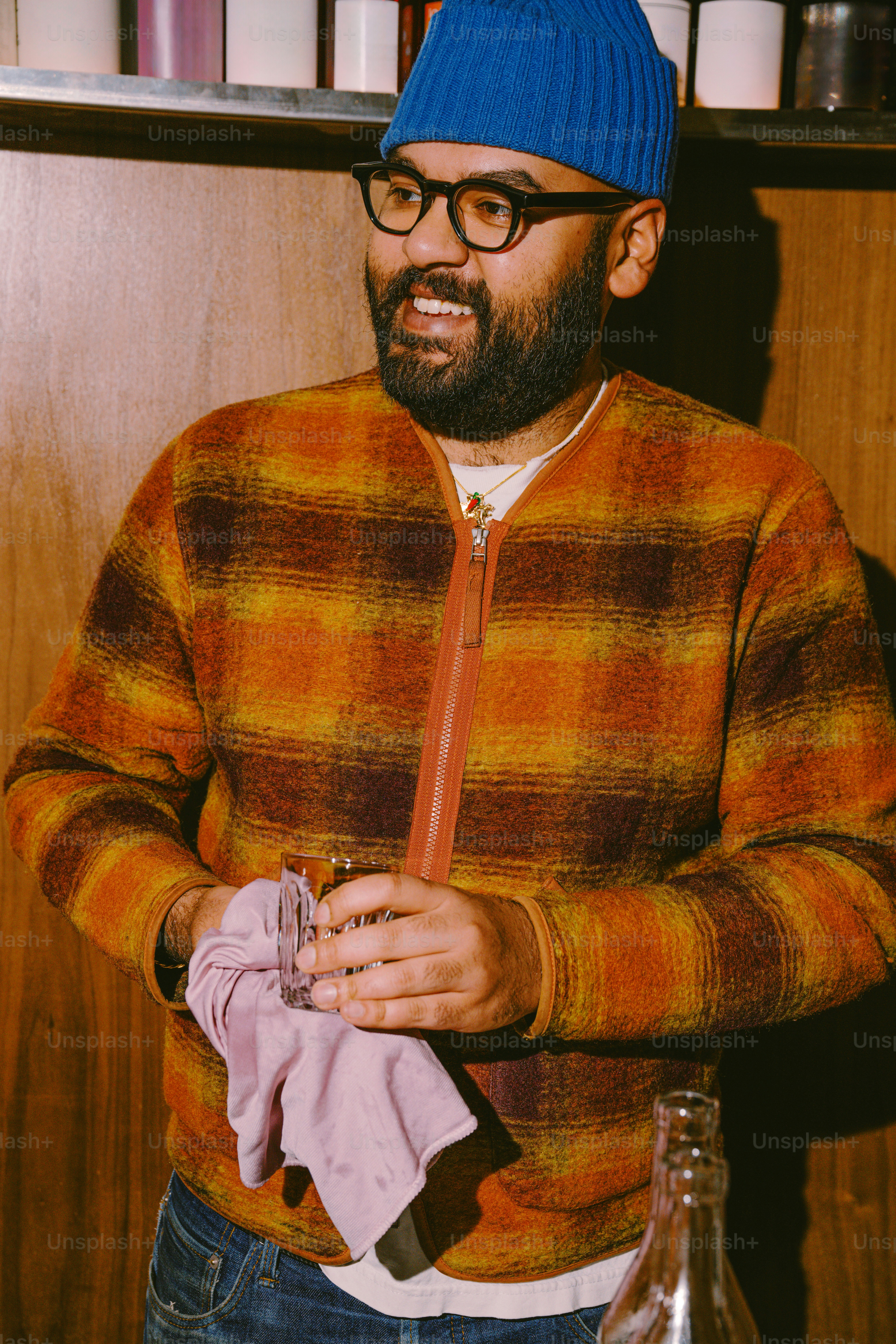 Man in beanie and plaid jacket holding a drink