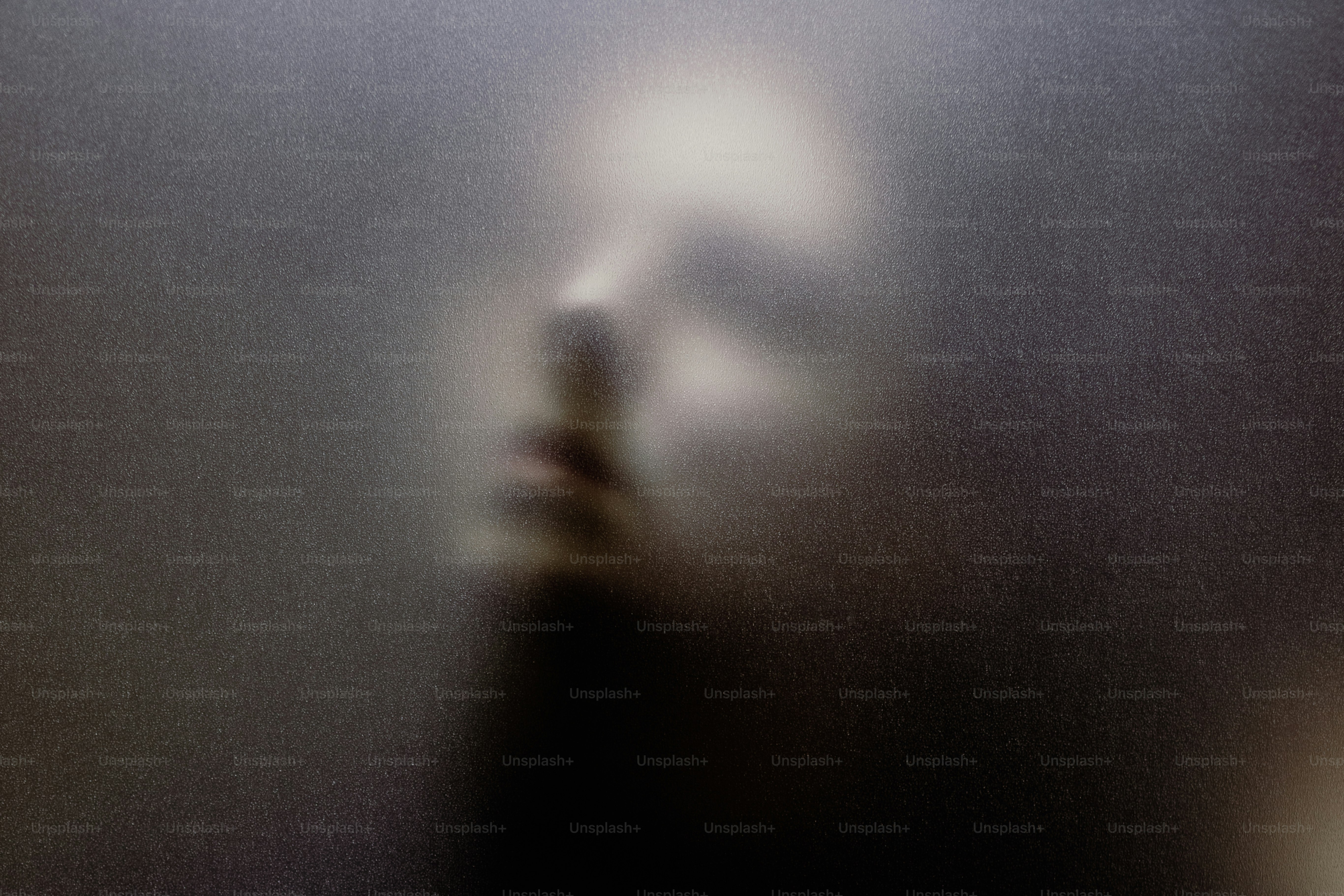 A blurred face seen through frosted glass