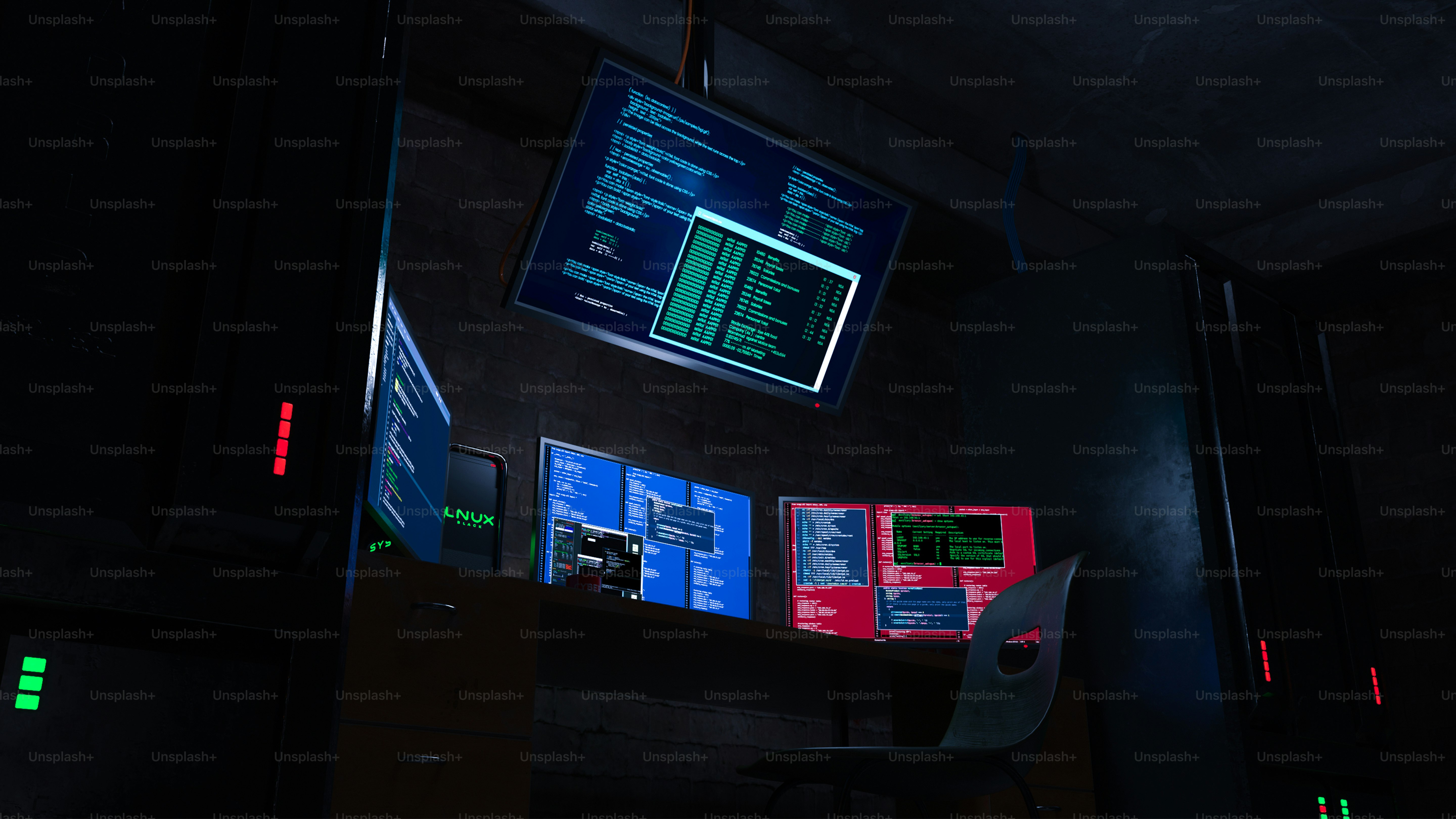 Multiple computer screens display code in a dark room.