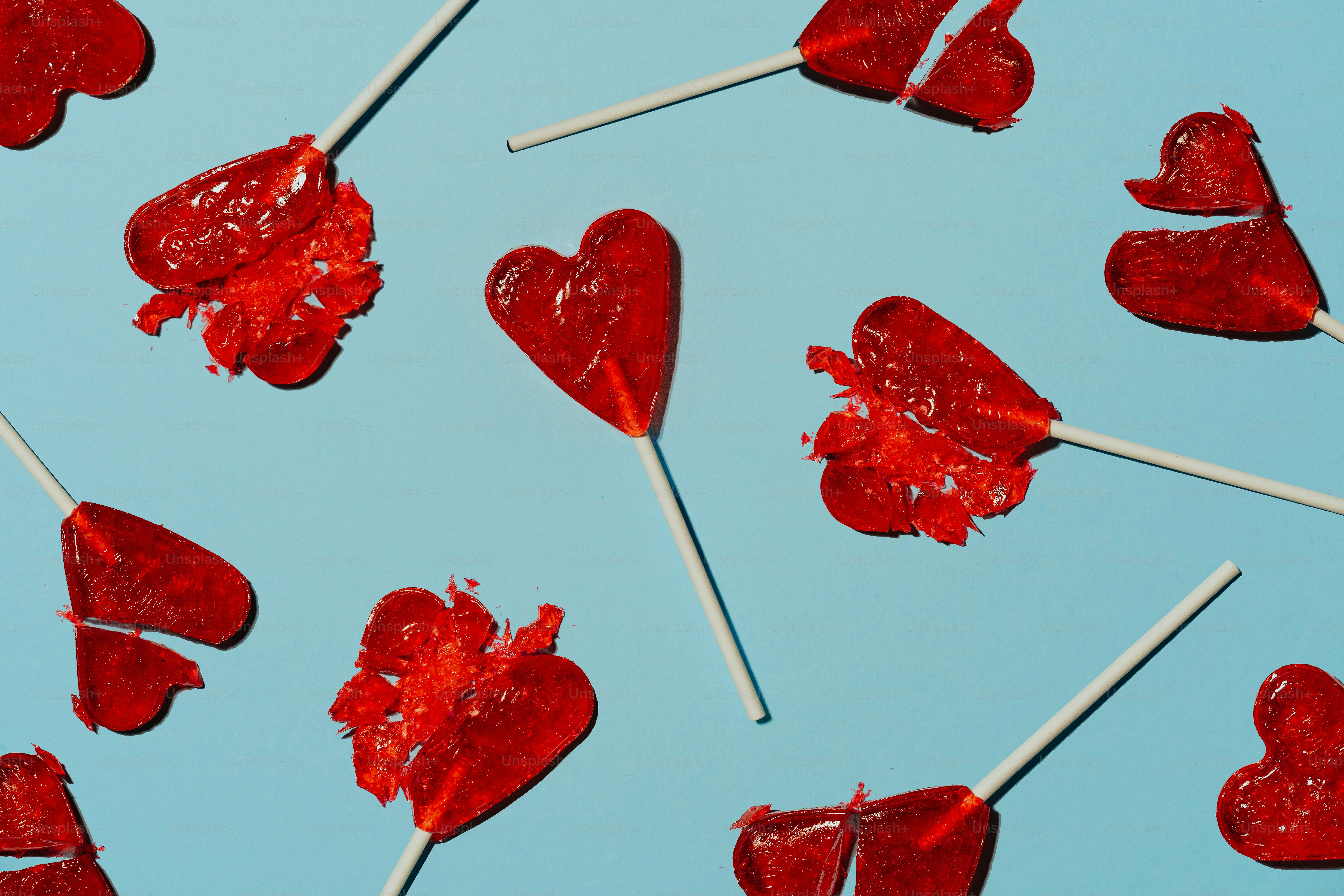 Rote, herzförmige Lutscher auf blauem Hintergrund verstreut