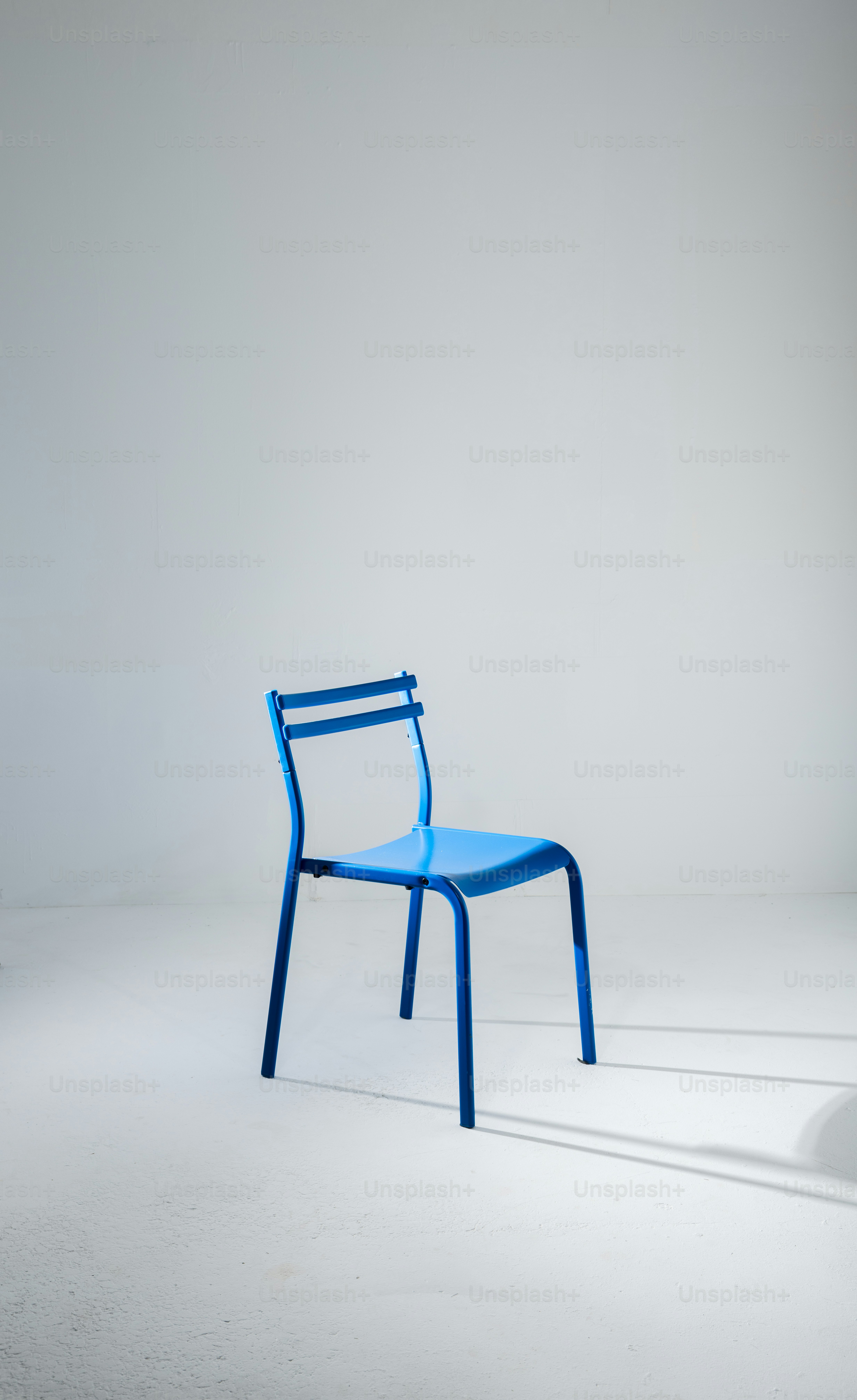 Una singola sedia blu in uno studio minimalista.