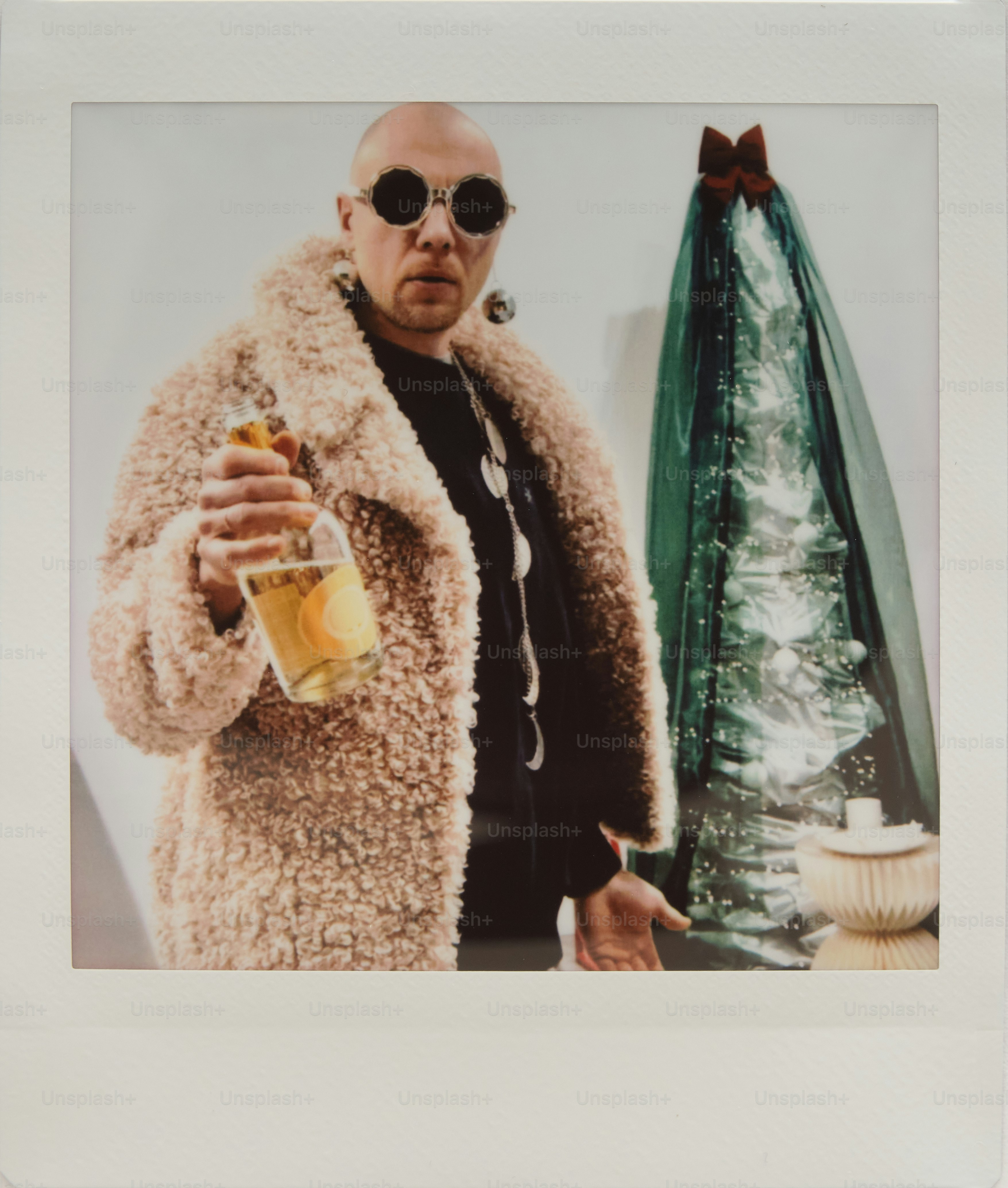 Bald man in fluffy coat holds champagne bottle near tree