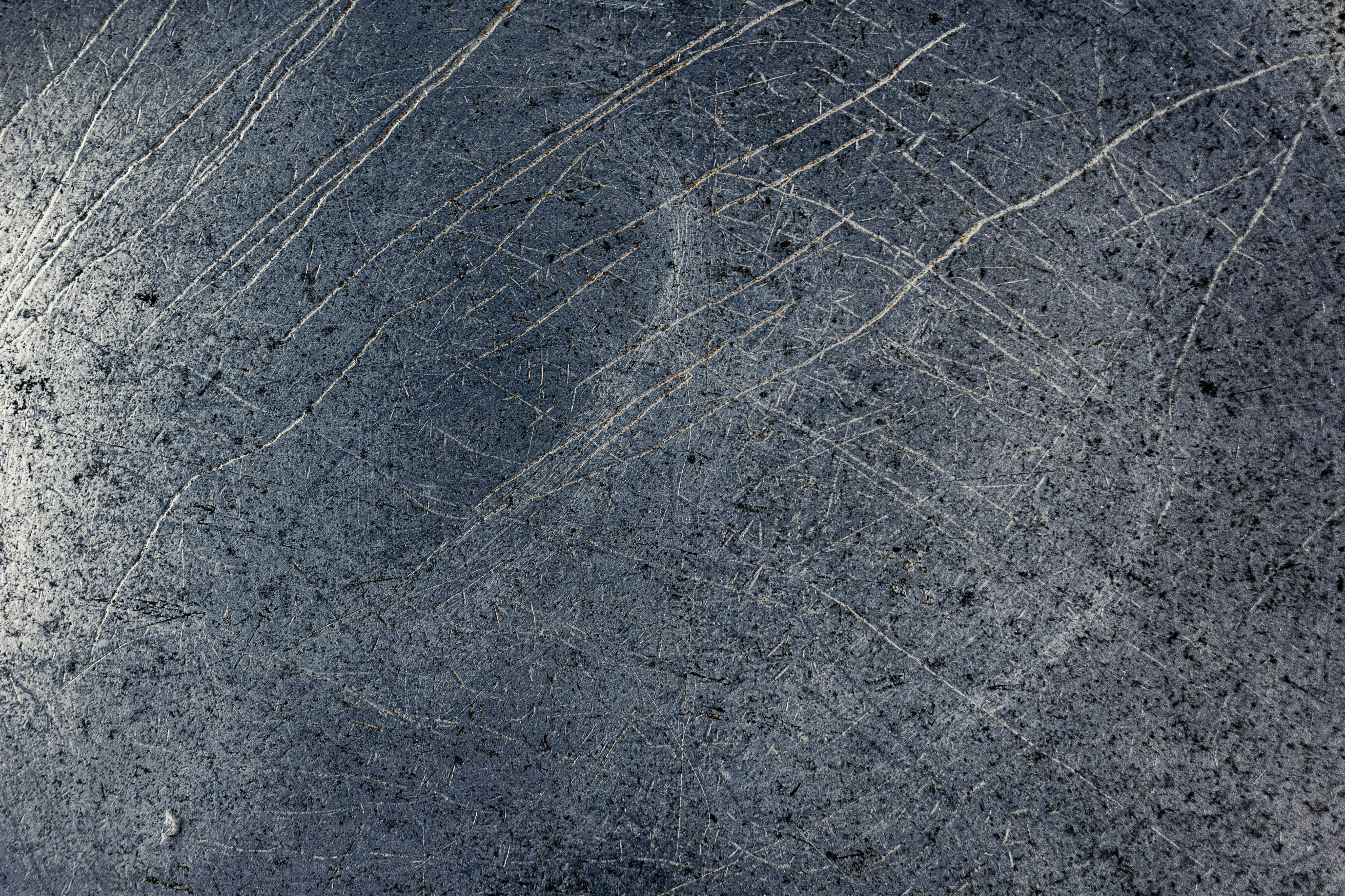 傷ついた金属表面に、テクスチャーのあるグレーの背景が描かれています