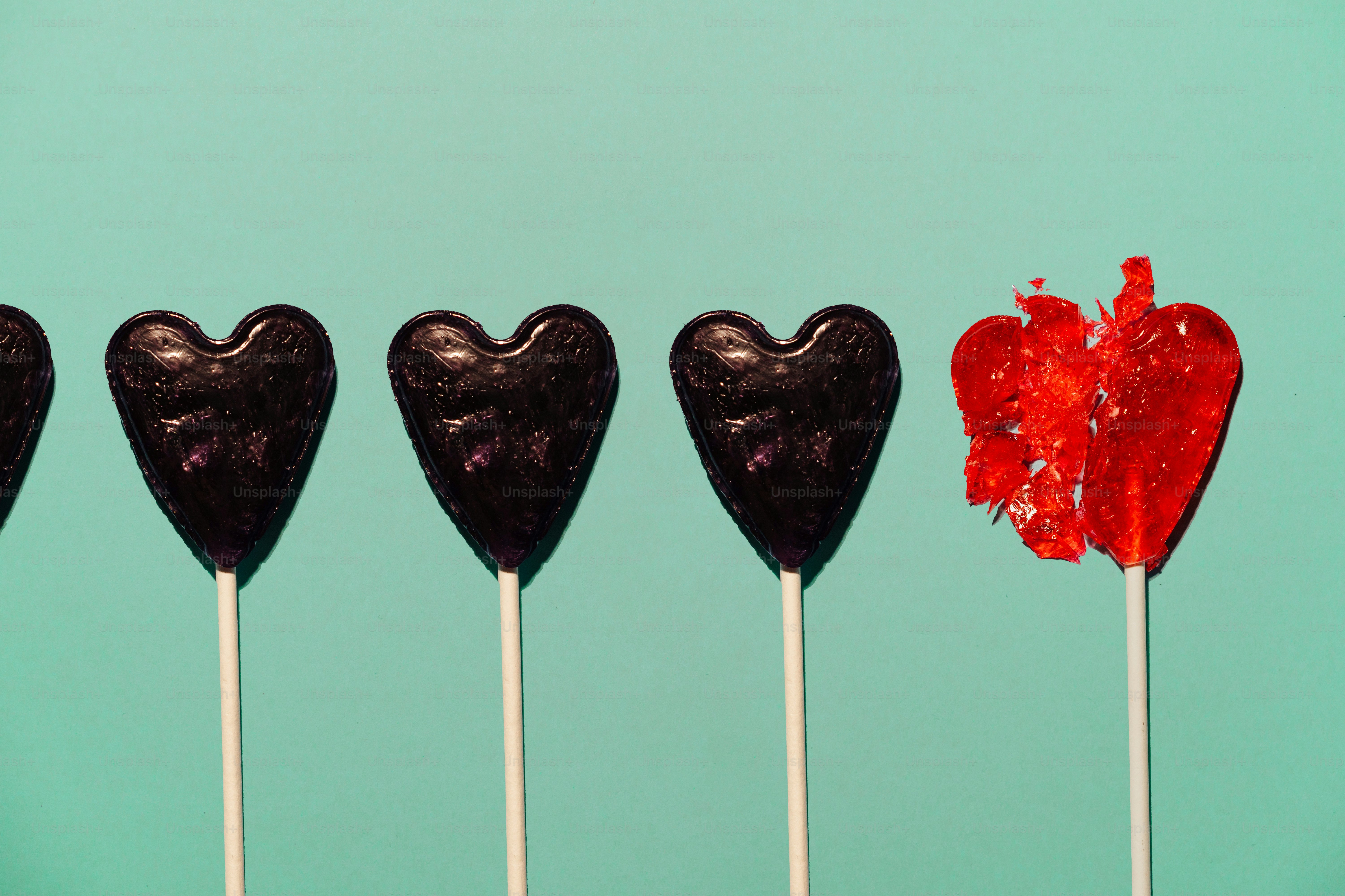 Reihe von schwarzen Herz-Lutschern mit einem roten, zerbrochenen