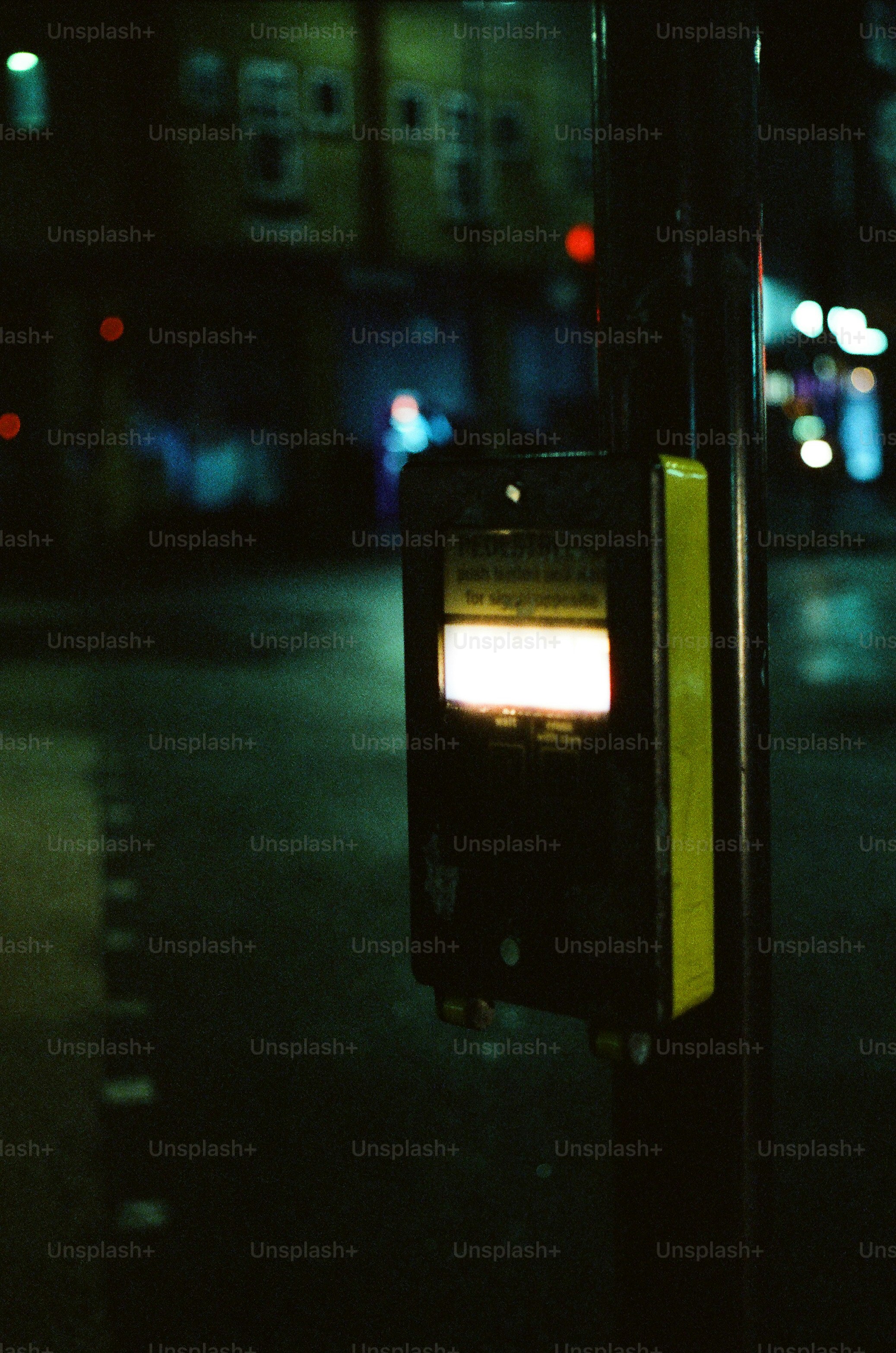A pedestrian crossing button glows at night.