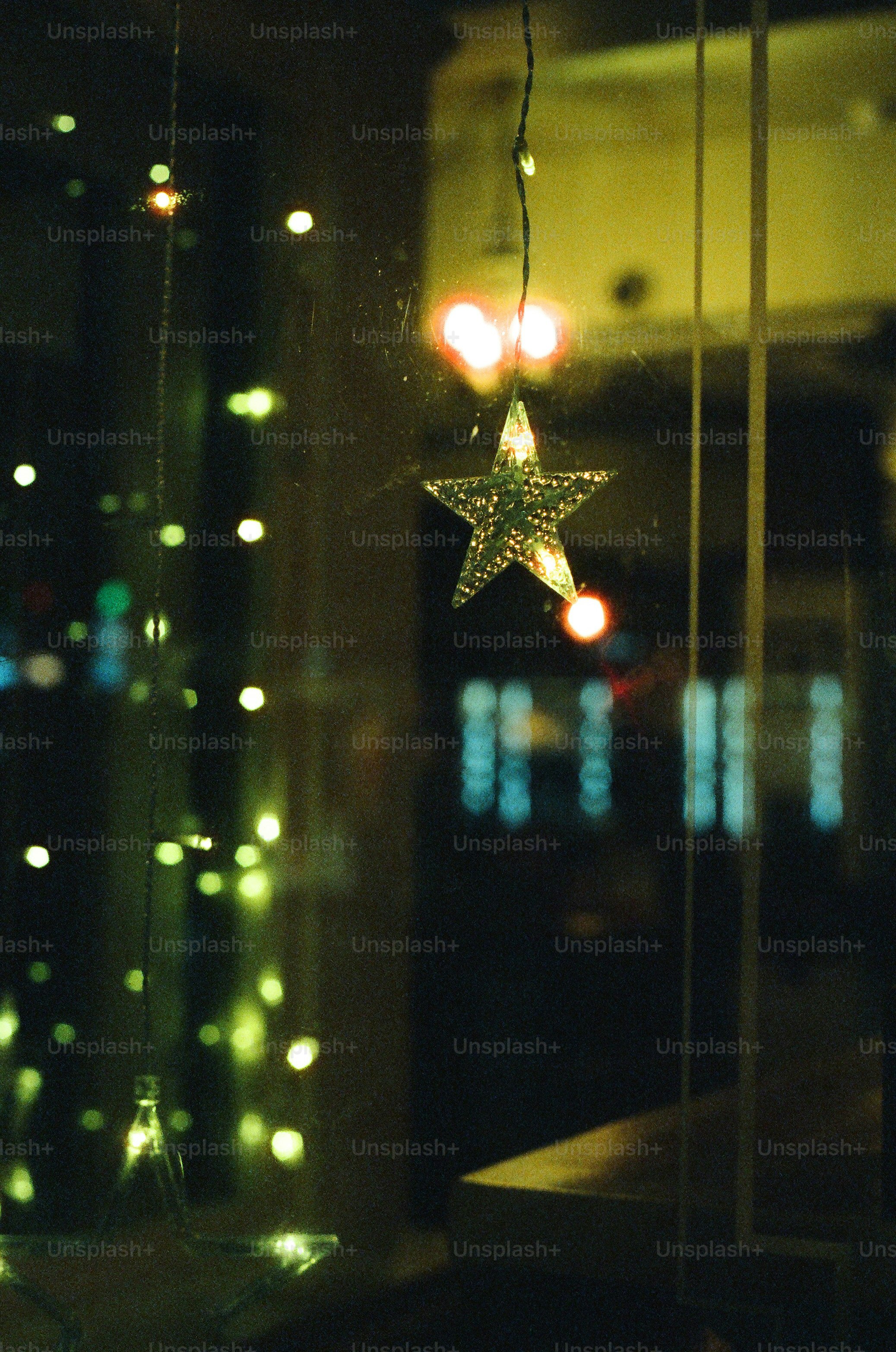 Sparkling star ornament hanging in window with bokeh lights.