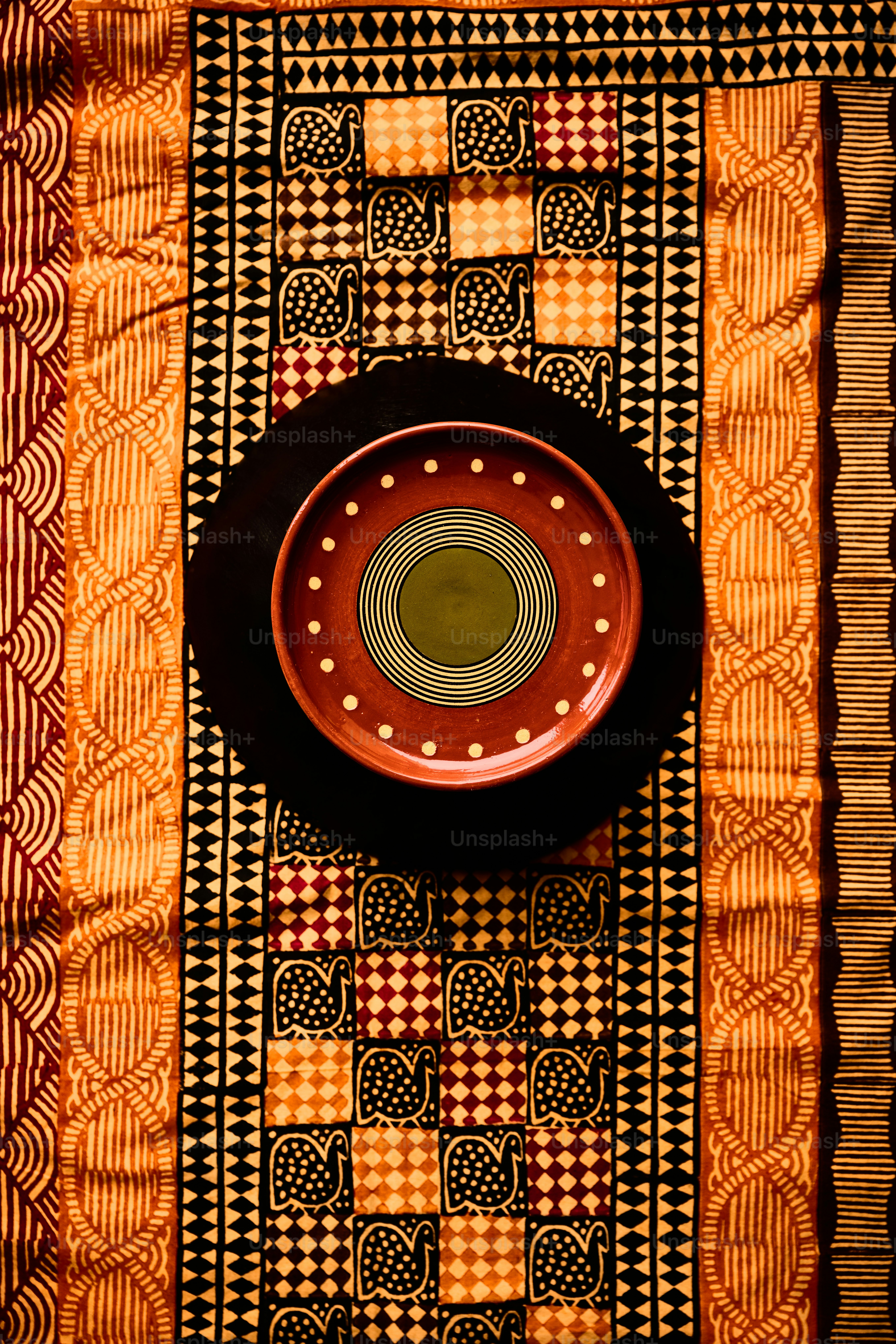 Une assiette décorative repose sur un textile à motifs.