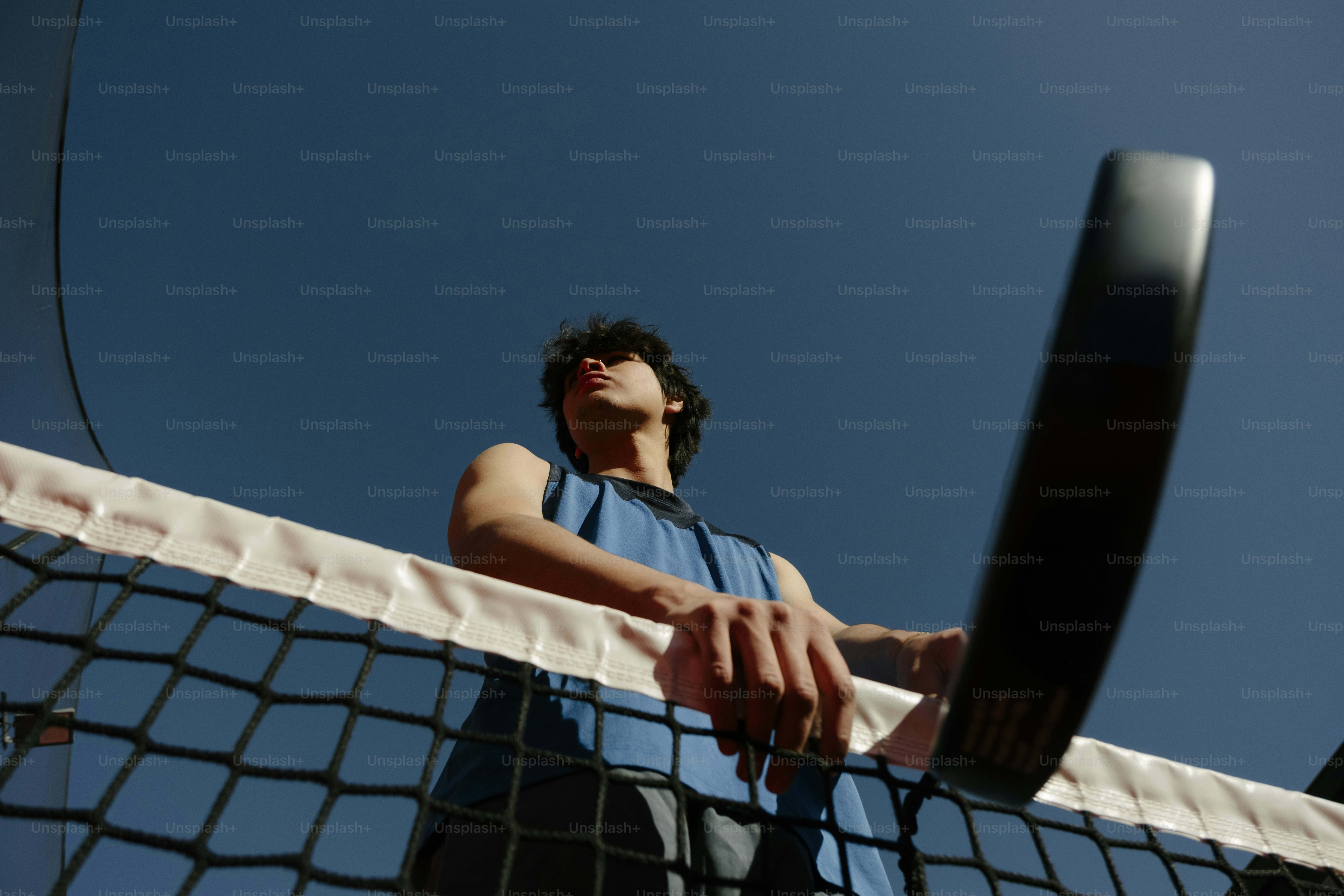 ネットのそばでテニスラケットを持つ男。