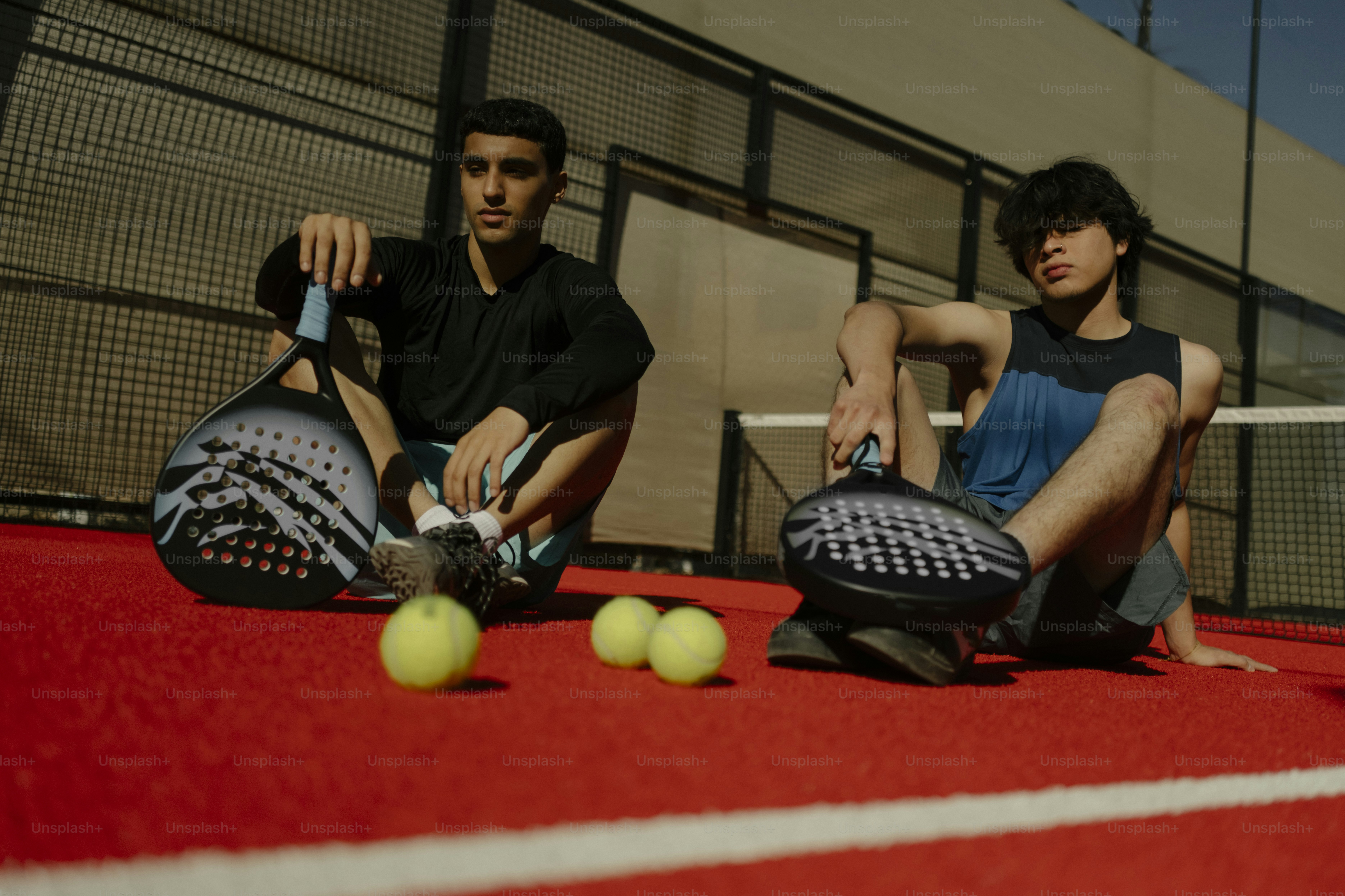 赤いコートにラケットを持った二人の若者