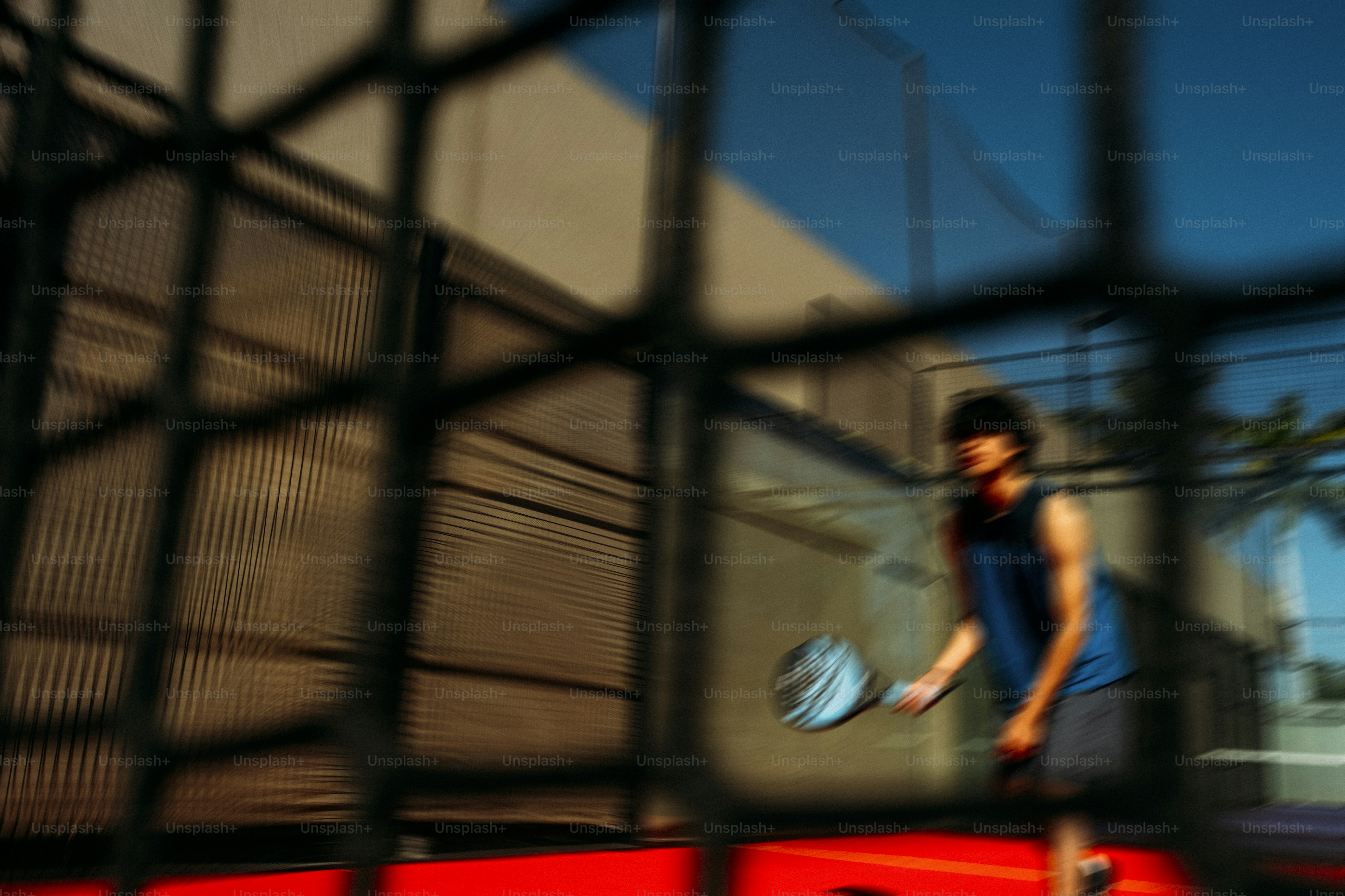 赤いコートでパデルテニスをしている男。