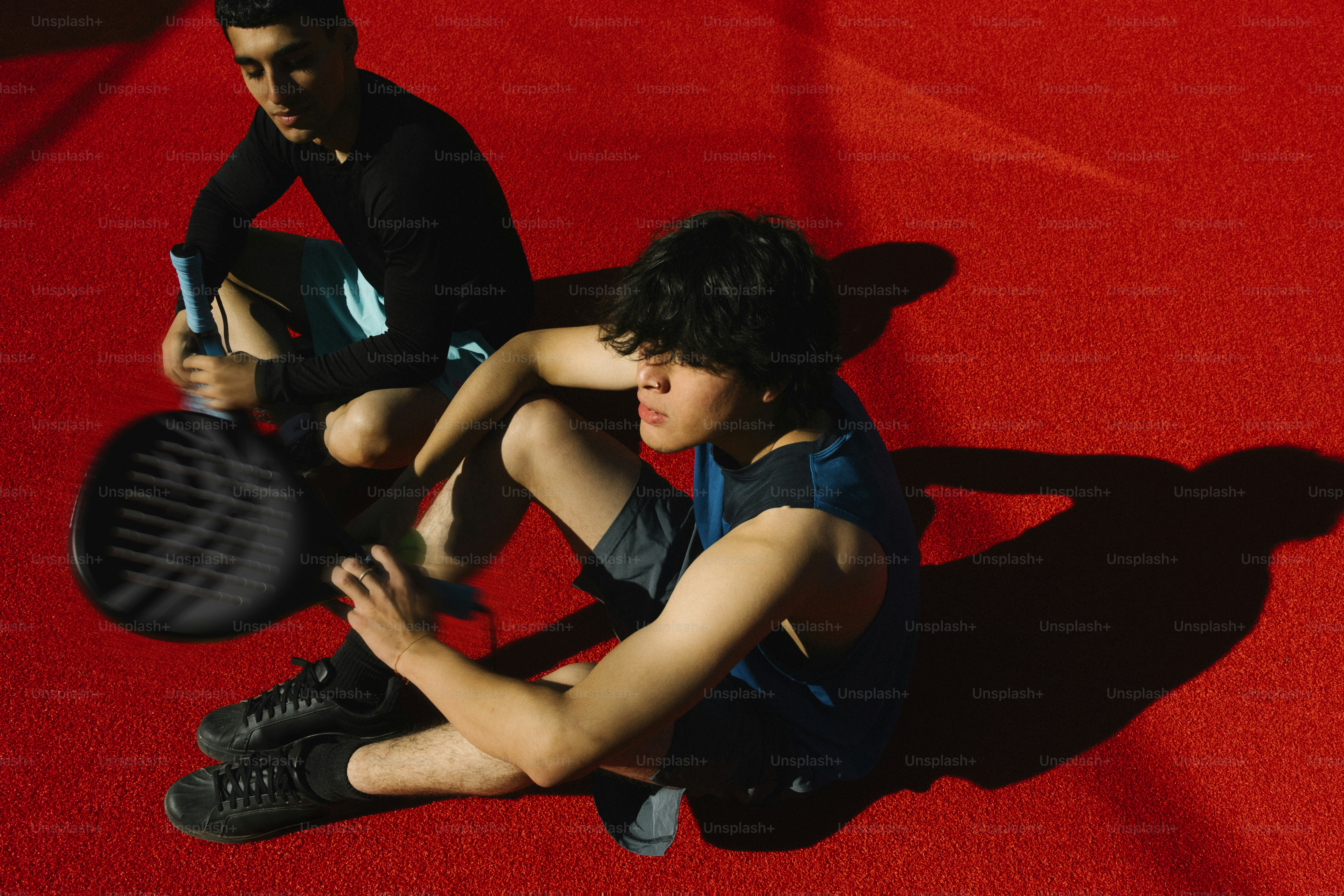 赤いコートにラケットを持った二人の若者