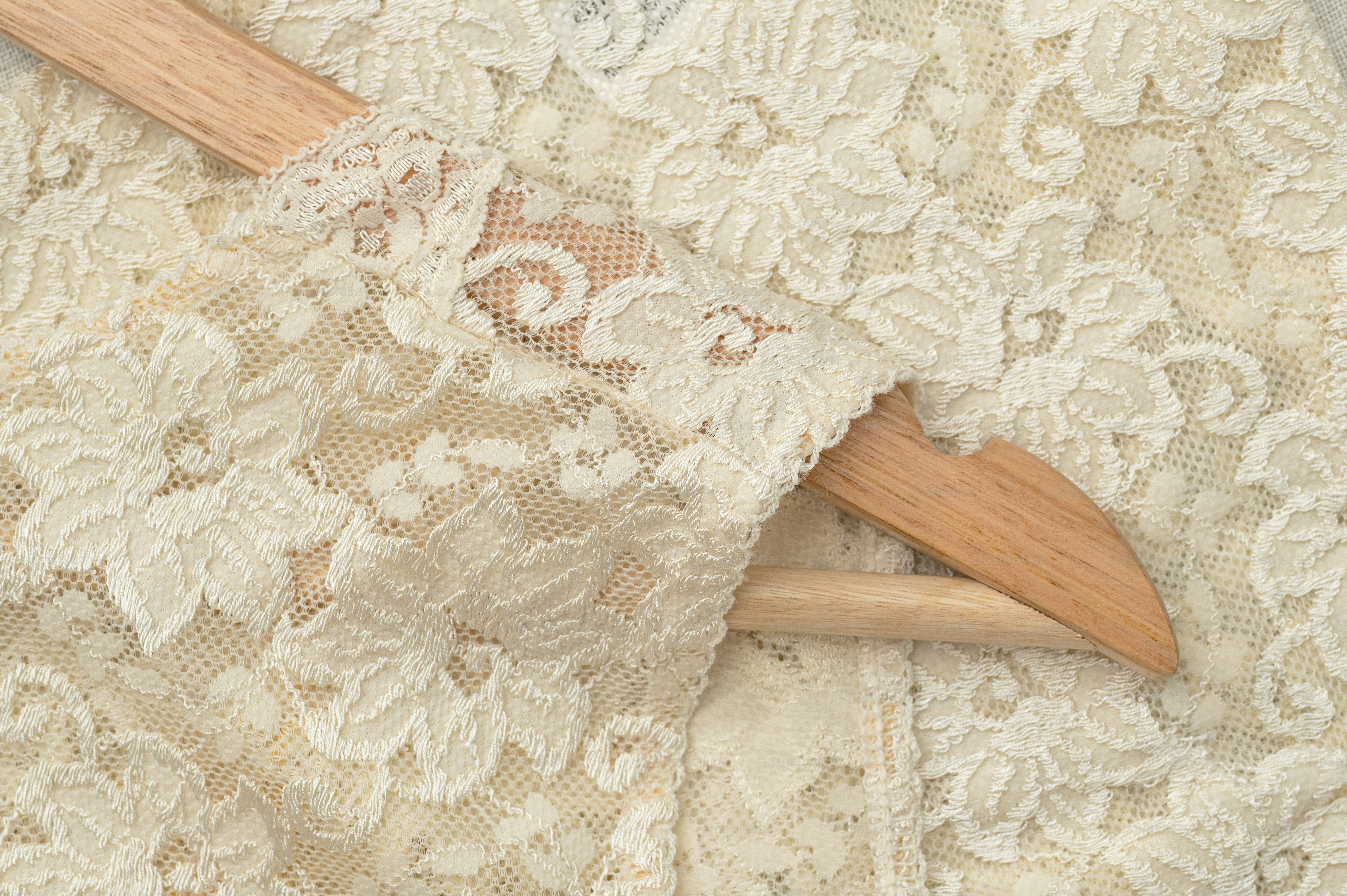 Close-up of delicate white lace fabric on a hanger.