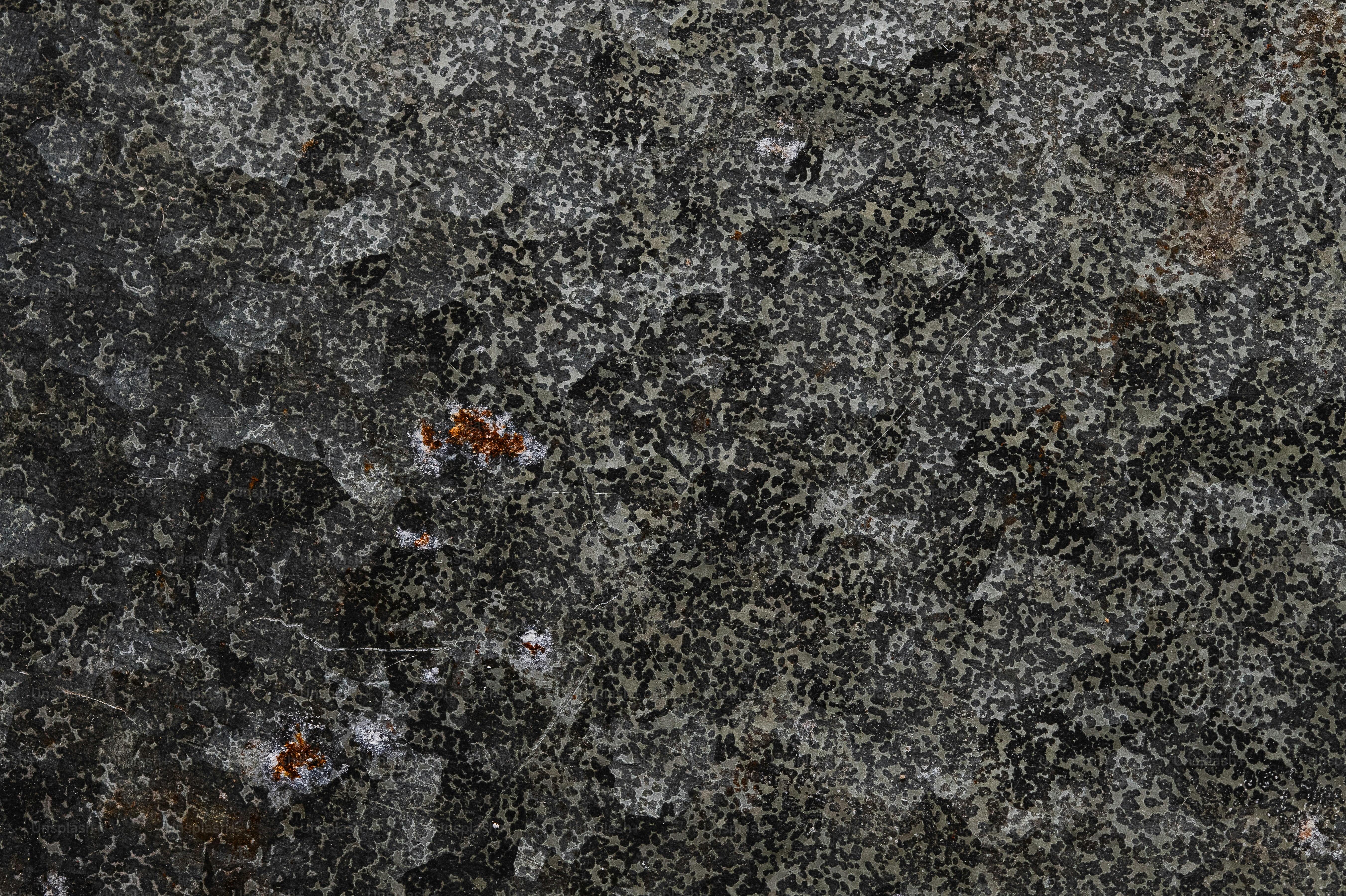 Close-up of a textured gray surface with small orange elements.