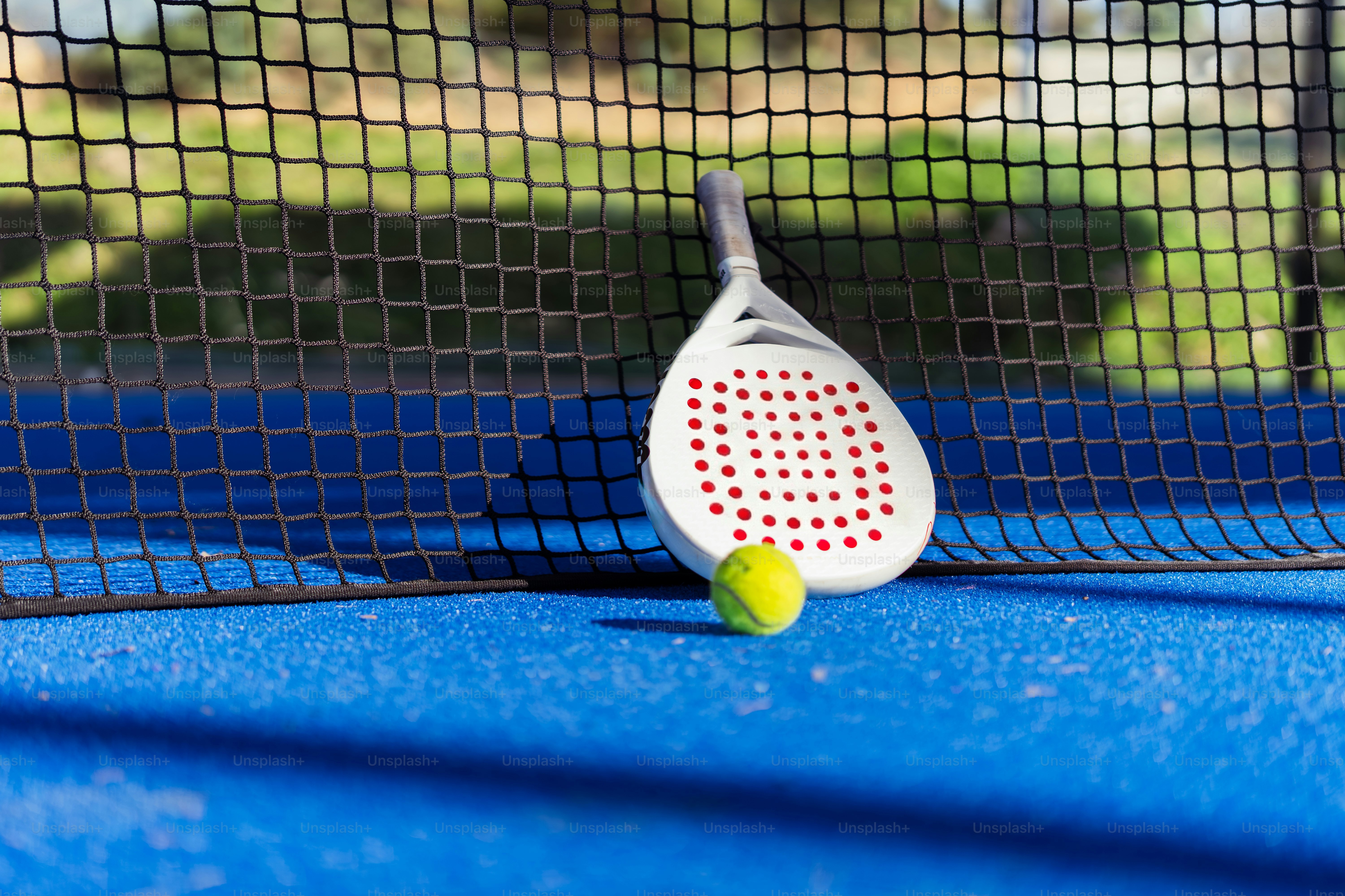 A padel racket and ball on a blue court. photo – Game Image on Unsplash