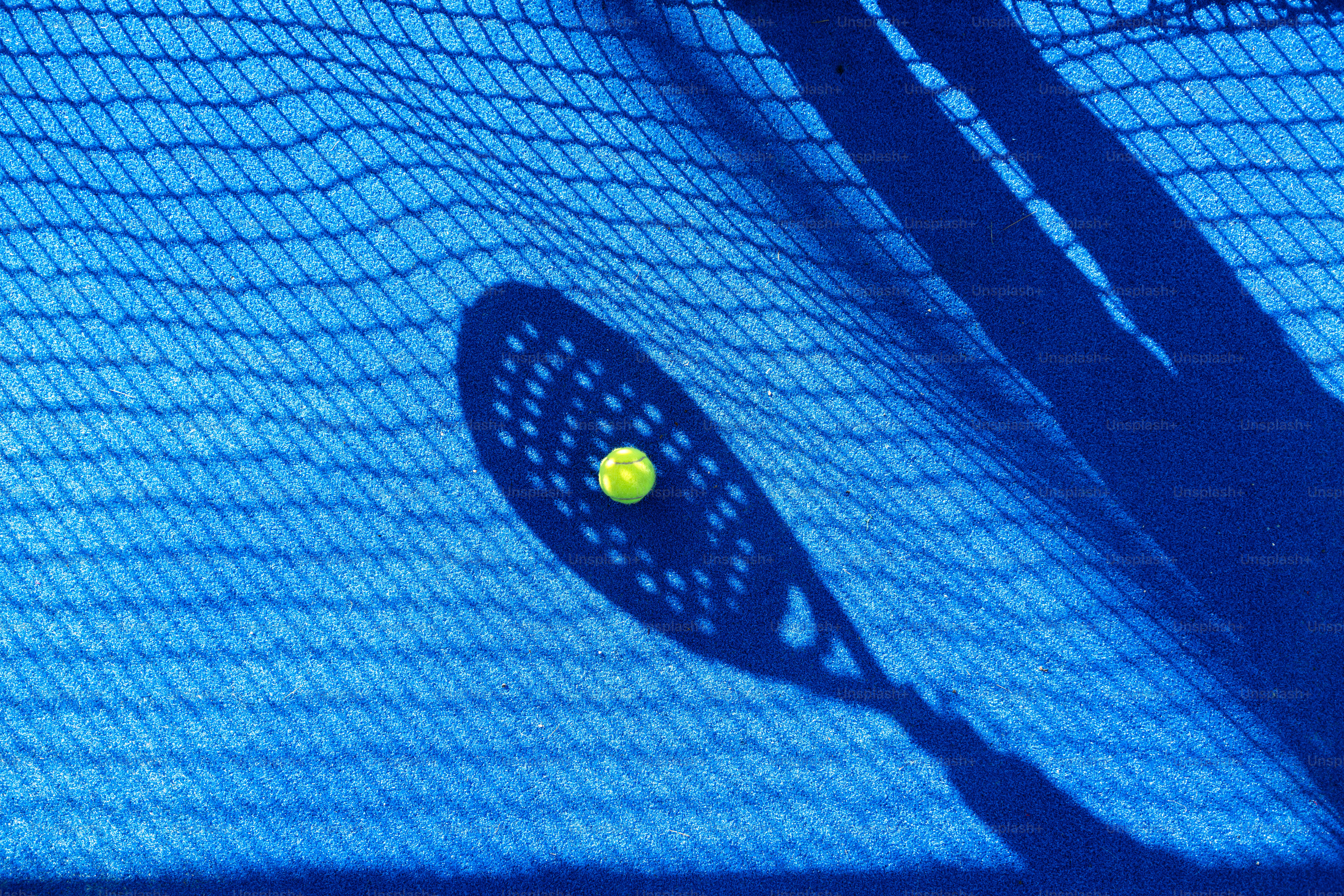 A padel racket and ball on a blue court. photo – Game Image on Unsplash