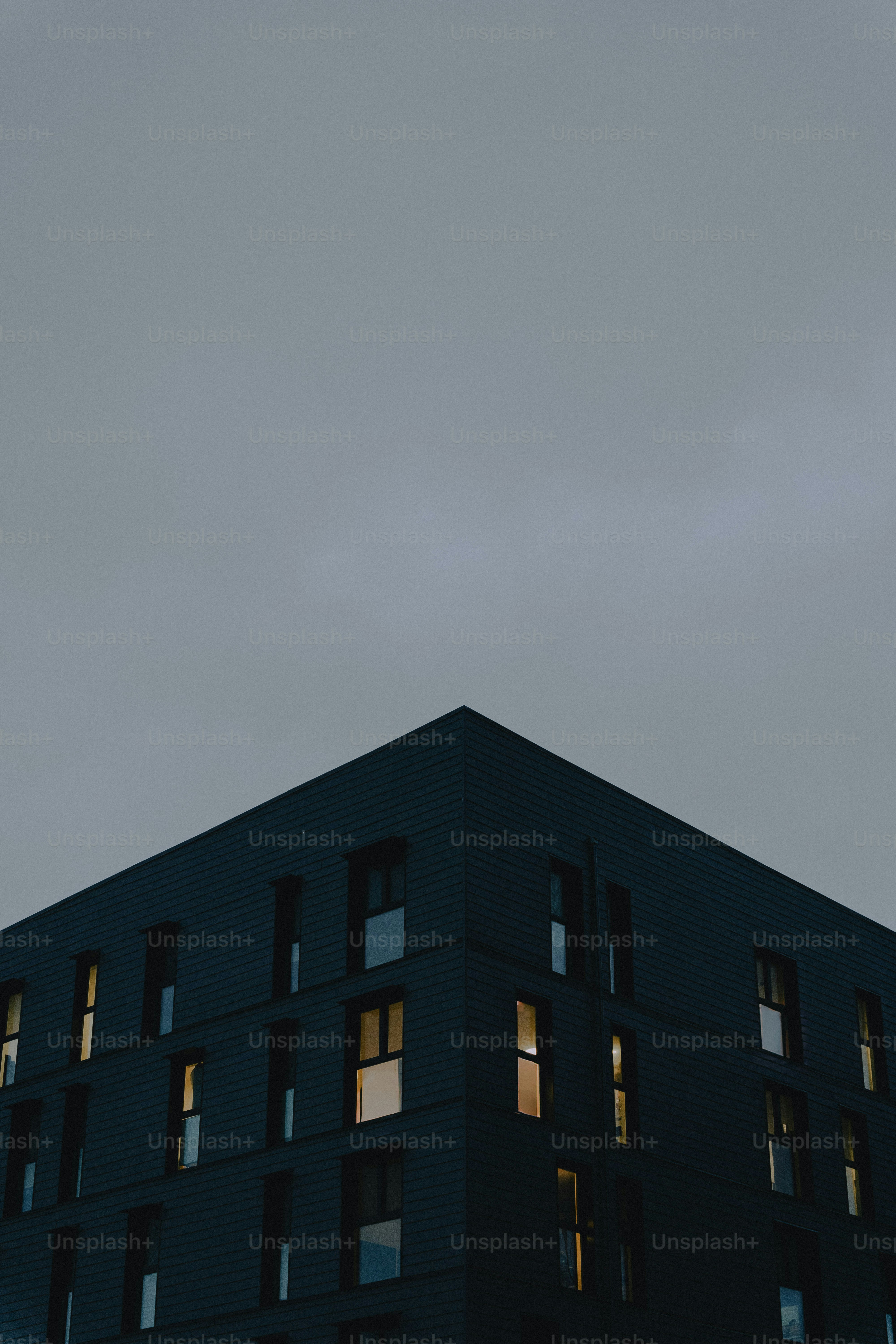 Modern building with illuminated windows under a cloudy sky
