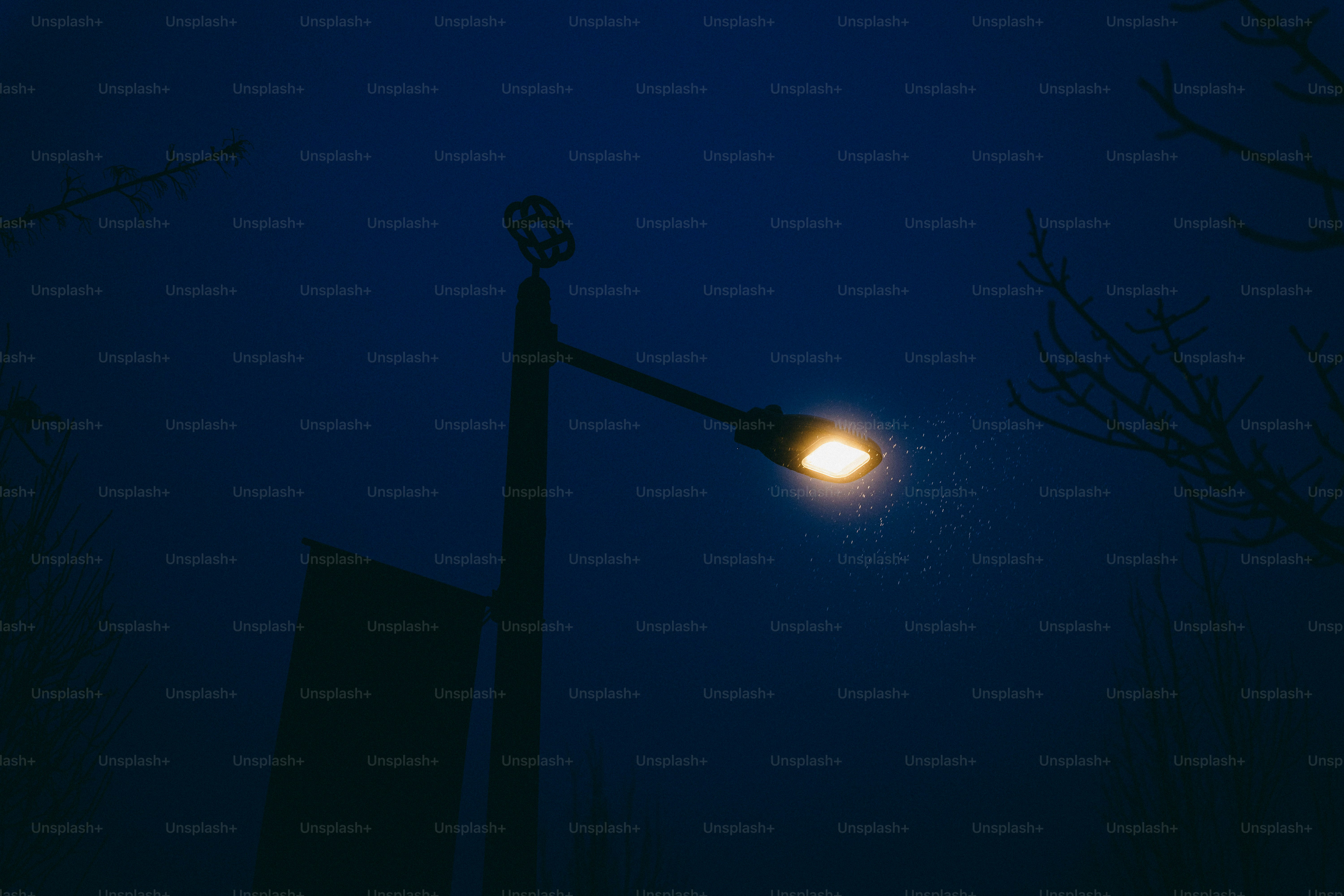 A lone street lamp glows on a dark, foggy night.