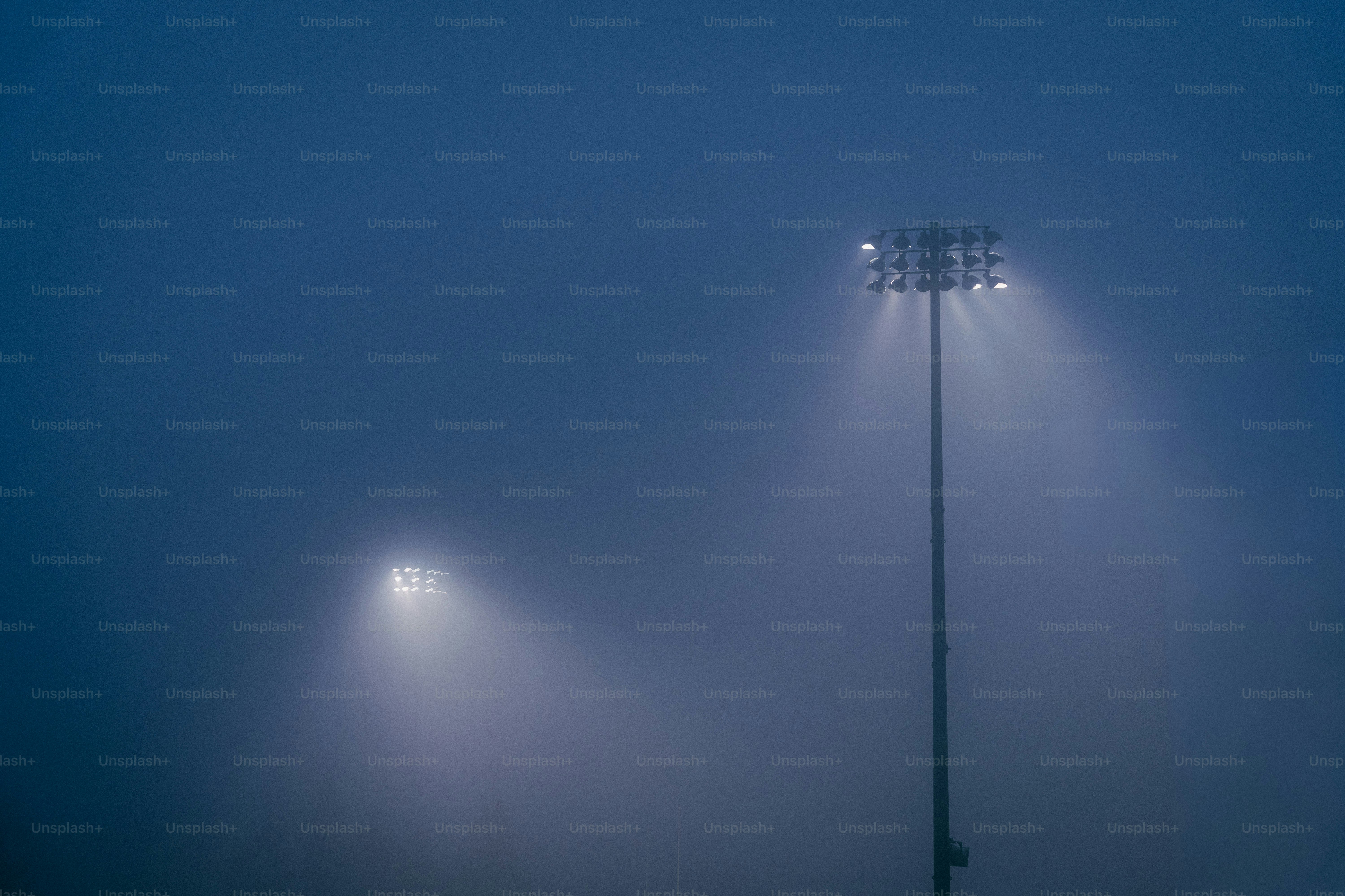 Two stadium lights glowing in thick fog