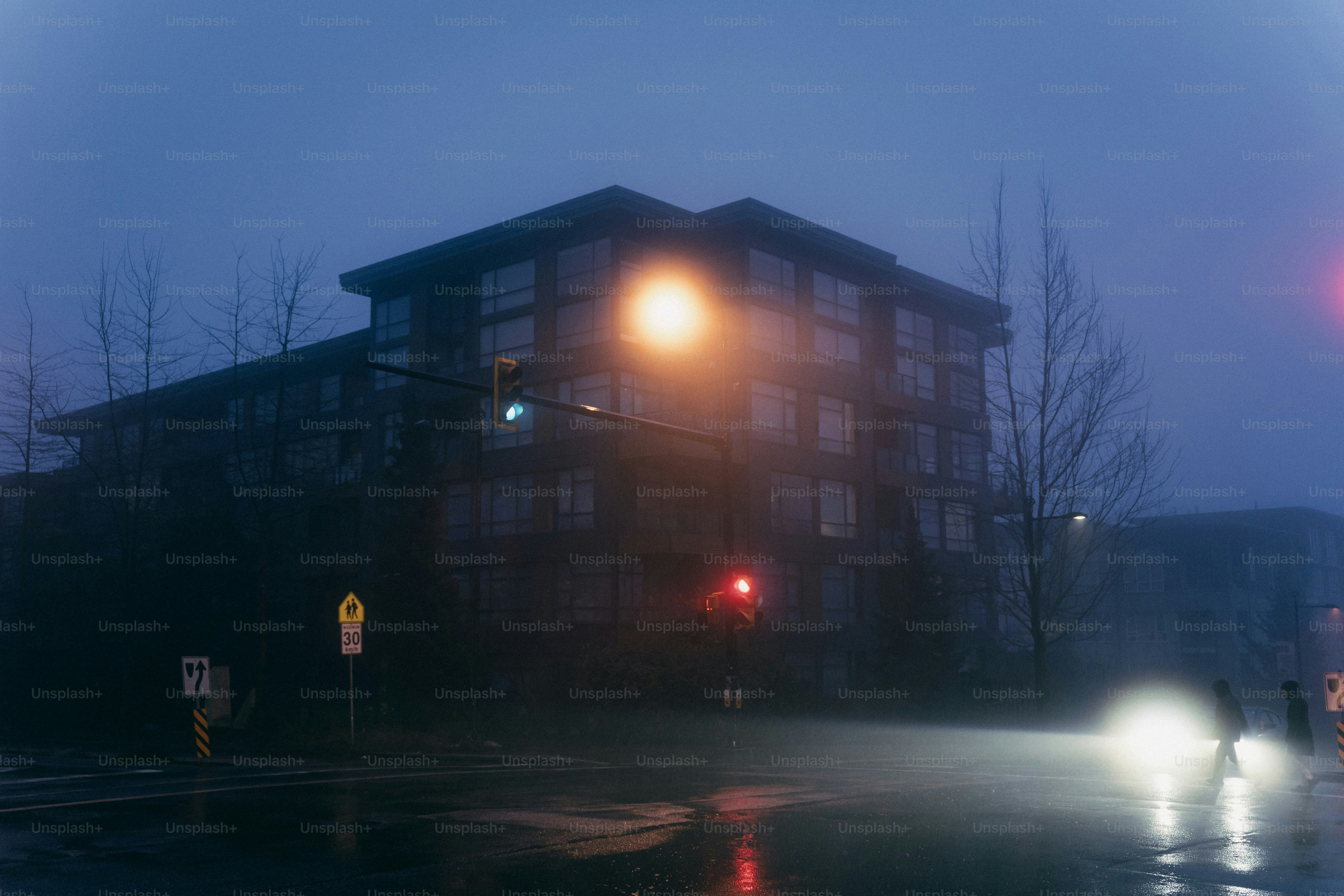 Foggy street scene with building and traffic lights.