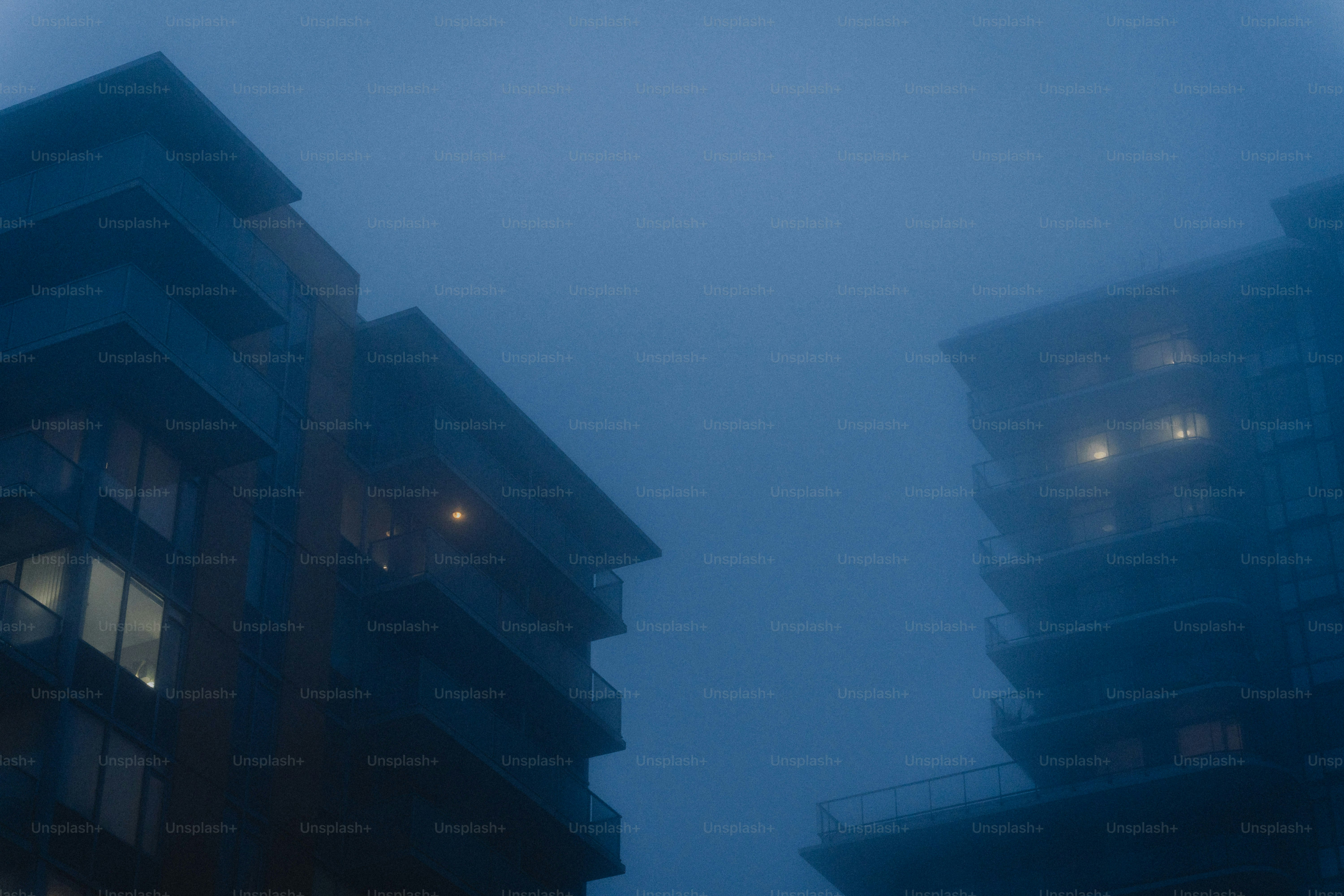 Two buildings shrouded in thick, dark blue fog.