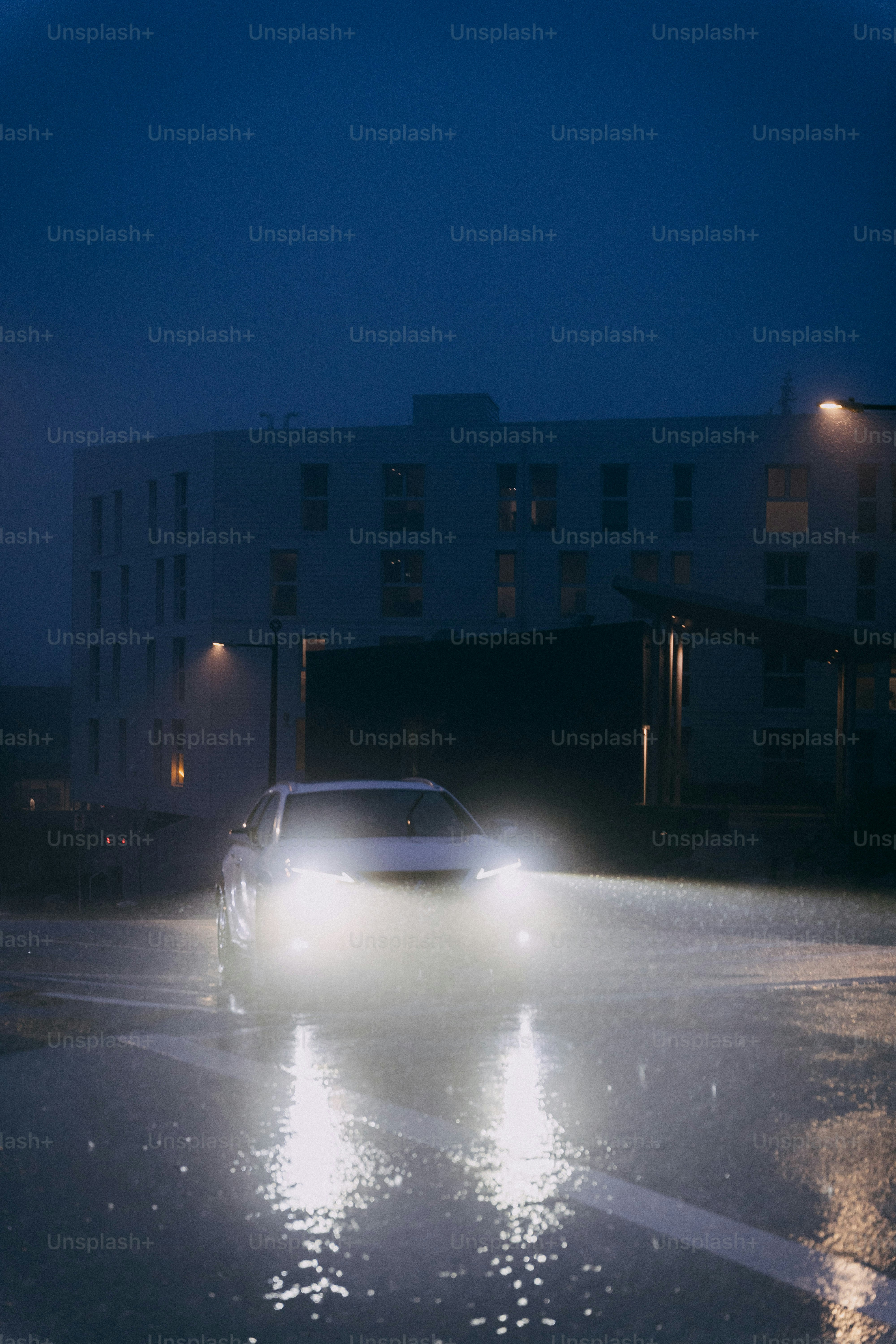 Car driving on wet road at night with headlights on