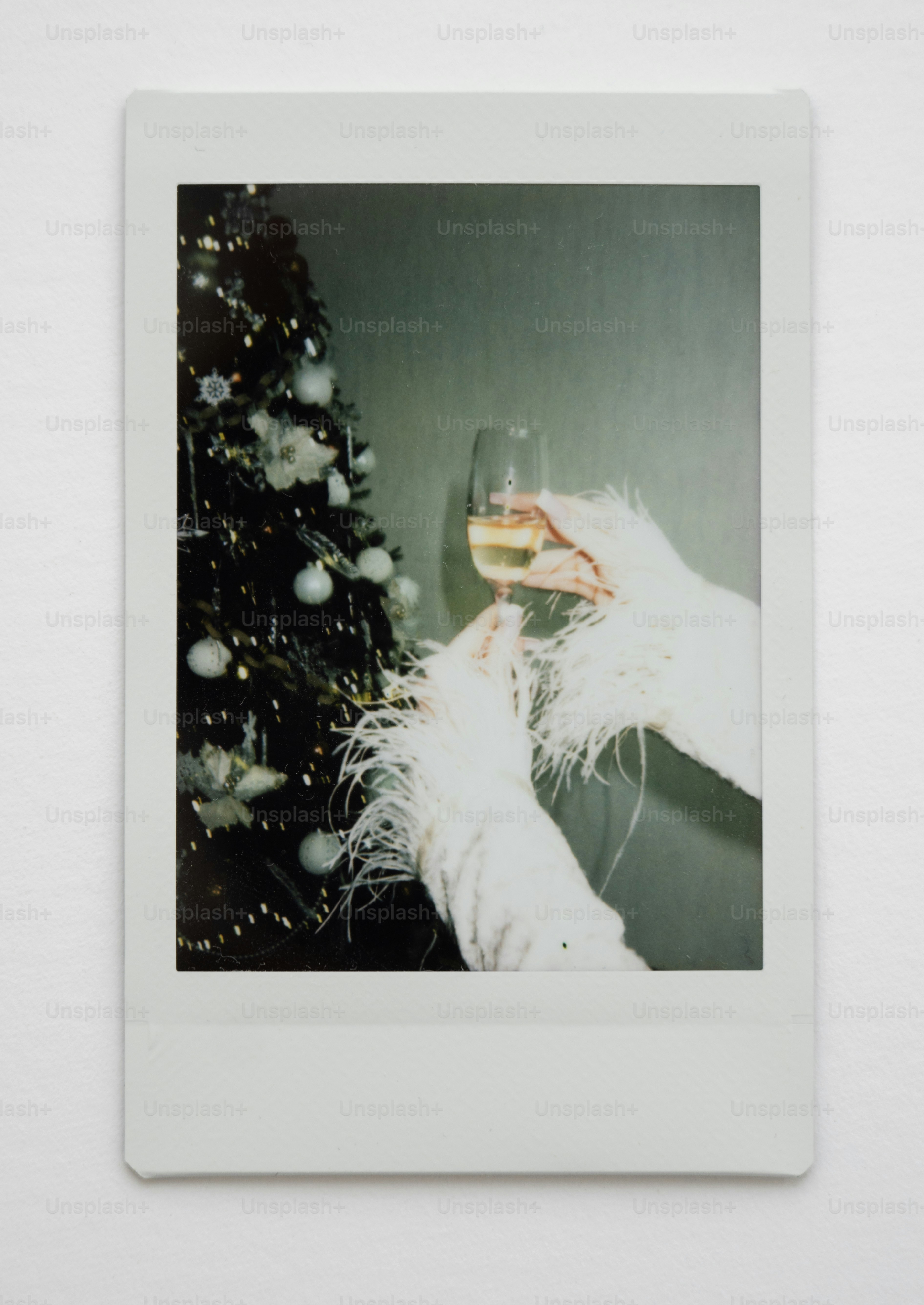 Hands in fluffy sleeves holding champagne by christmas tree