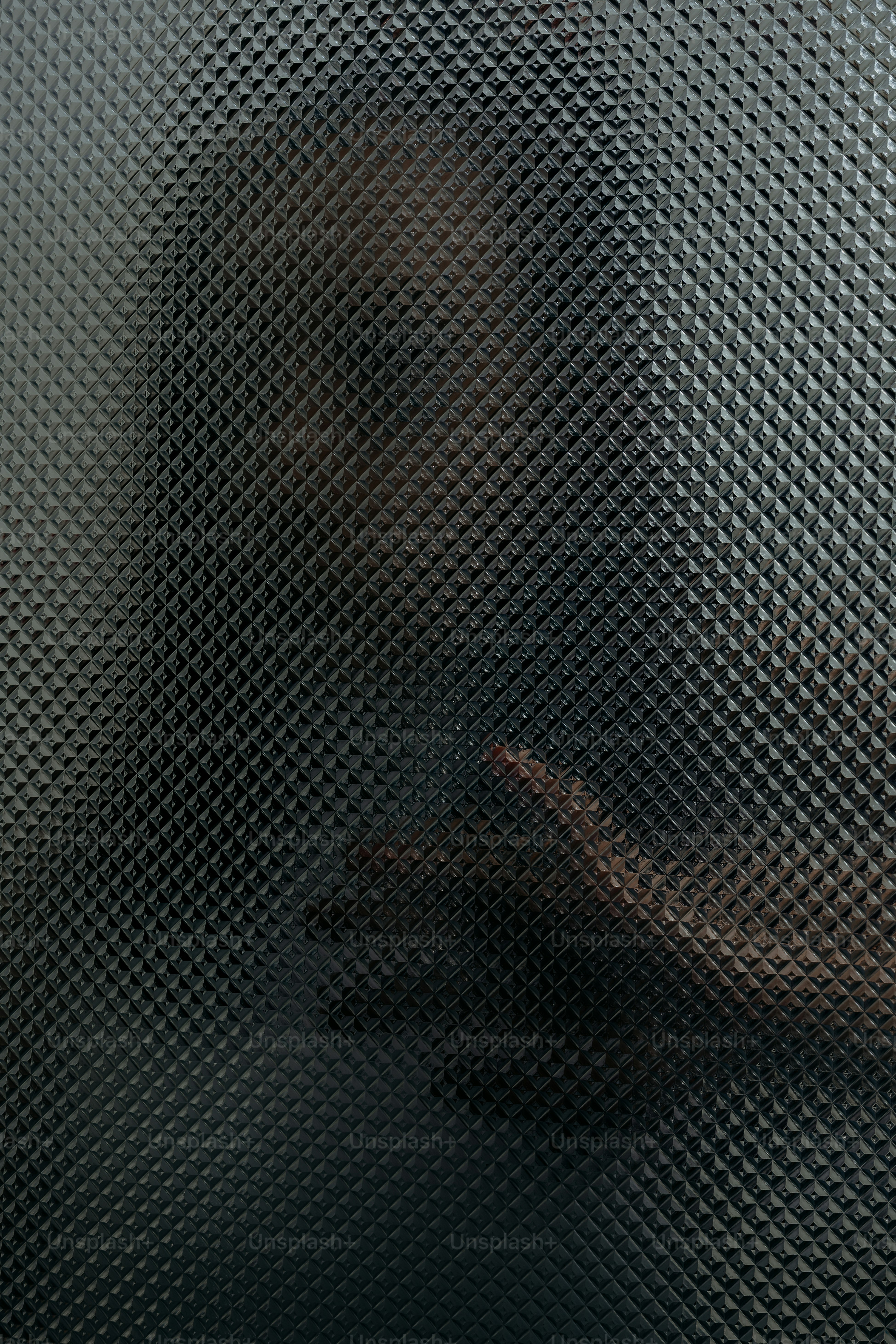 Person's silhouette seen through textured glass