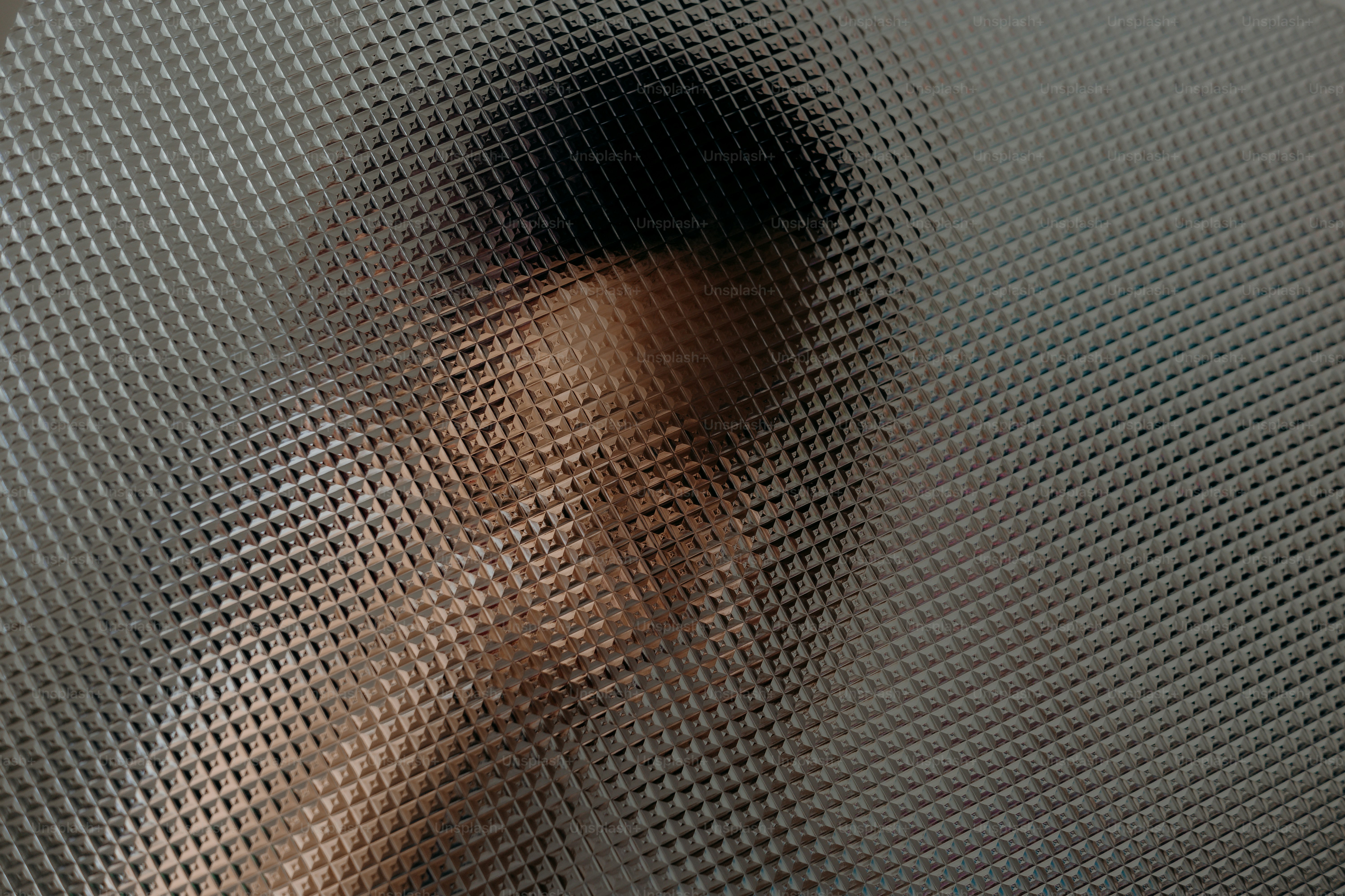 Blurred face seen through textured glass
