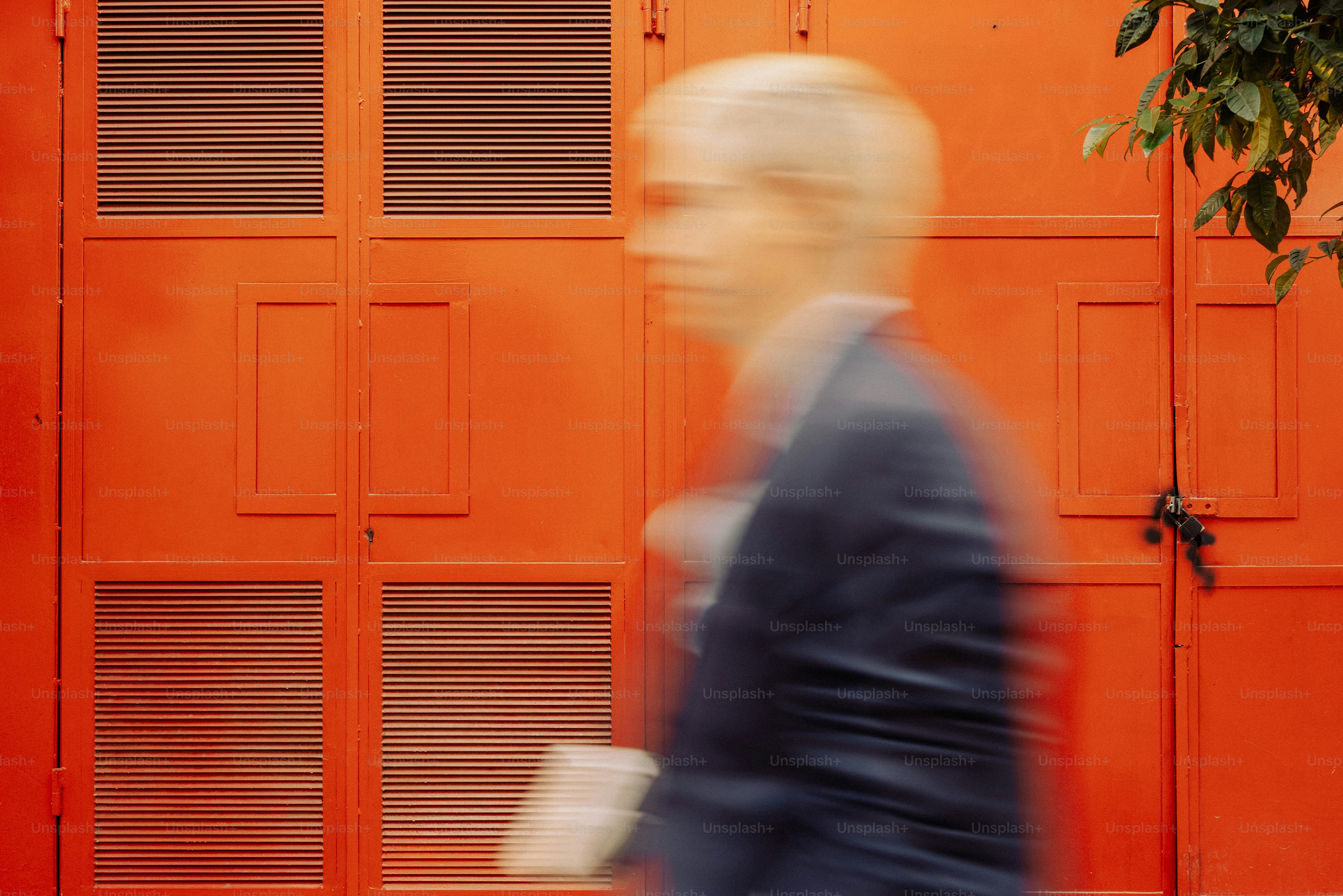 Blurred person in suit walks past orange door