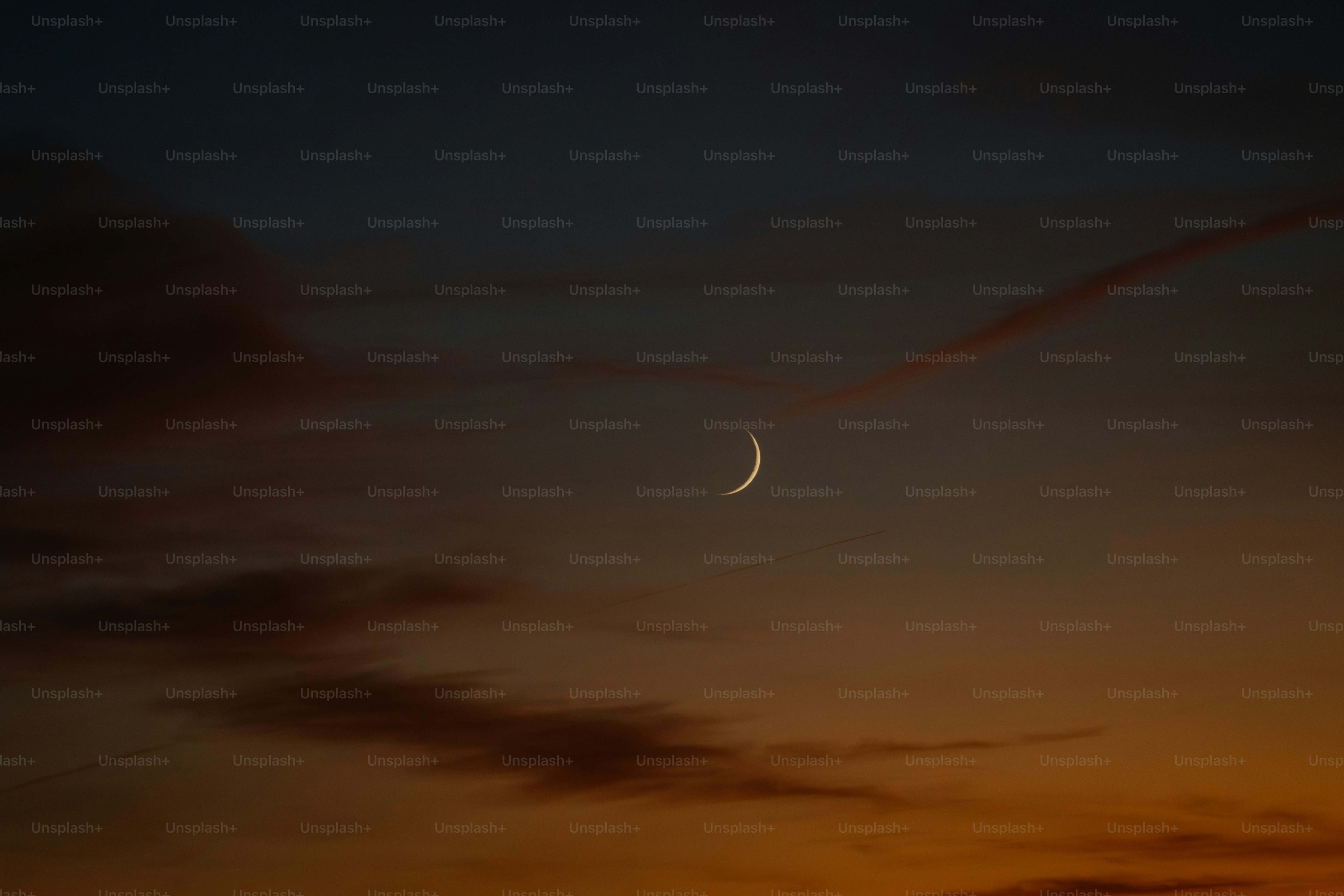 A crescent moon in a colorful twilight sky