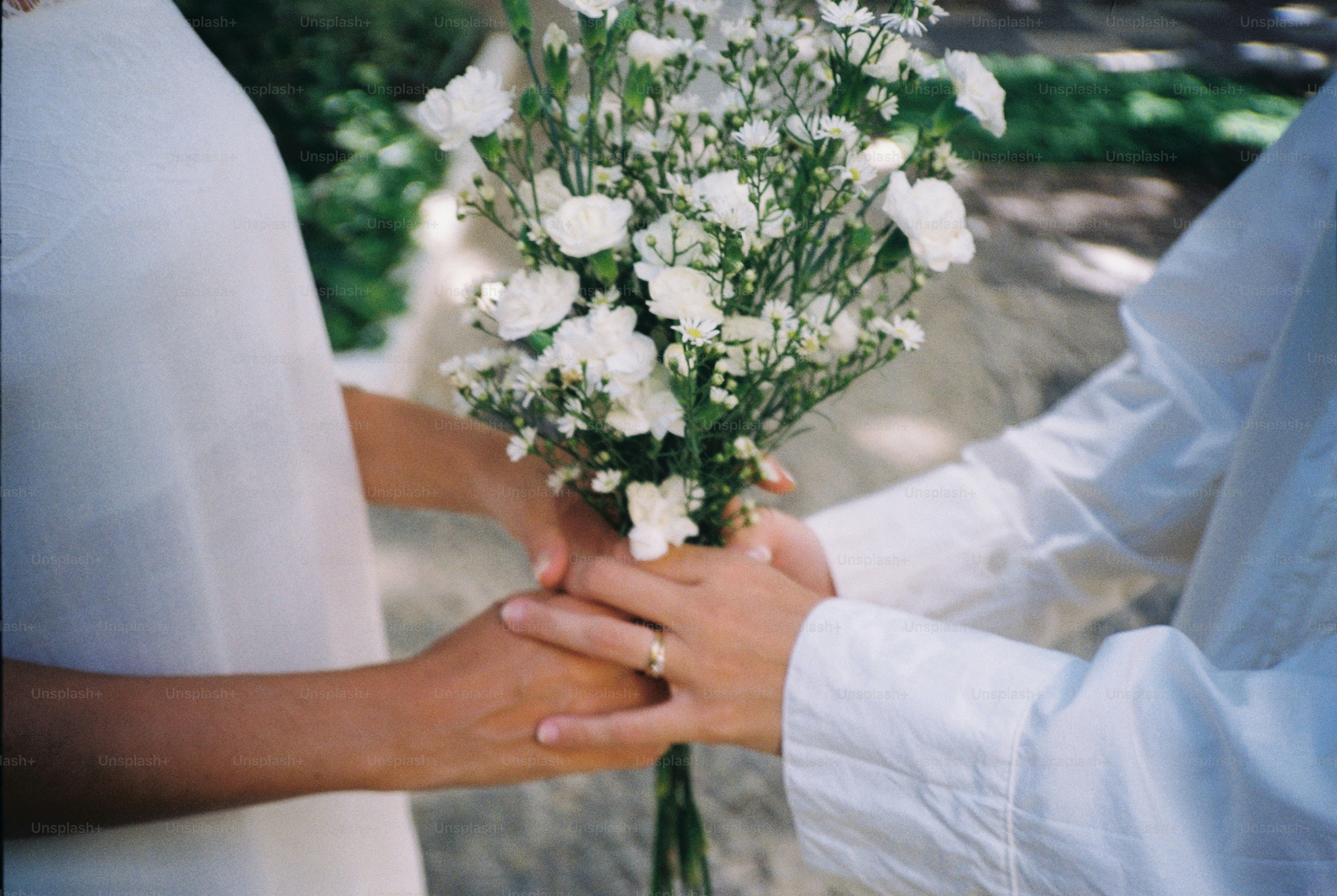Two people holding a bouquet of white flowers