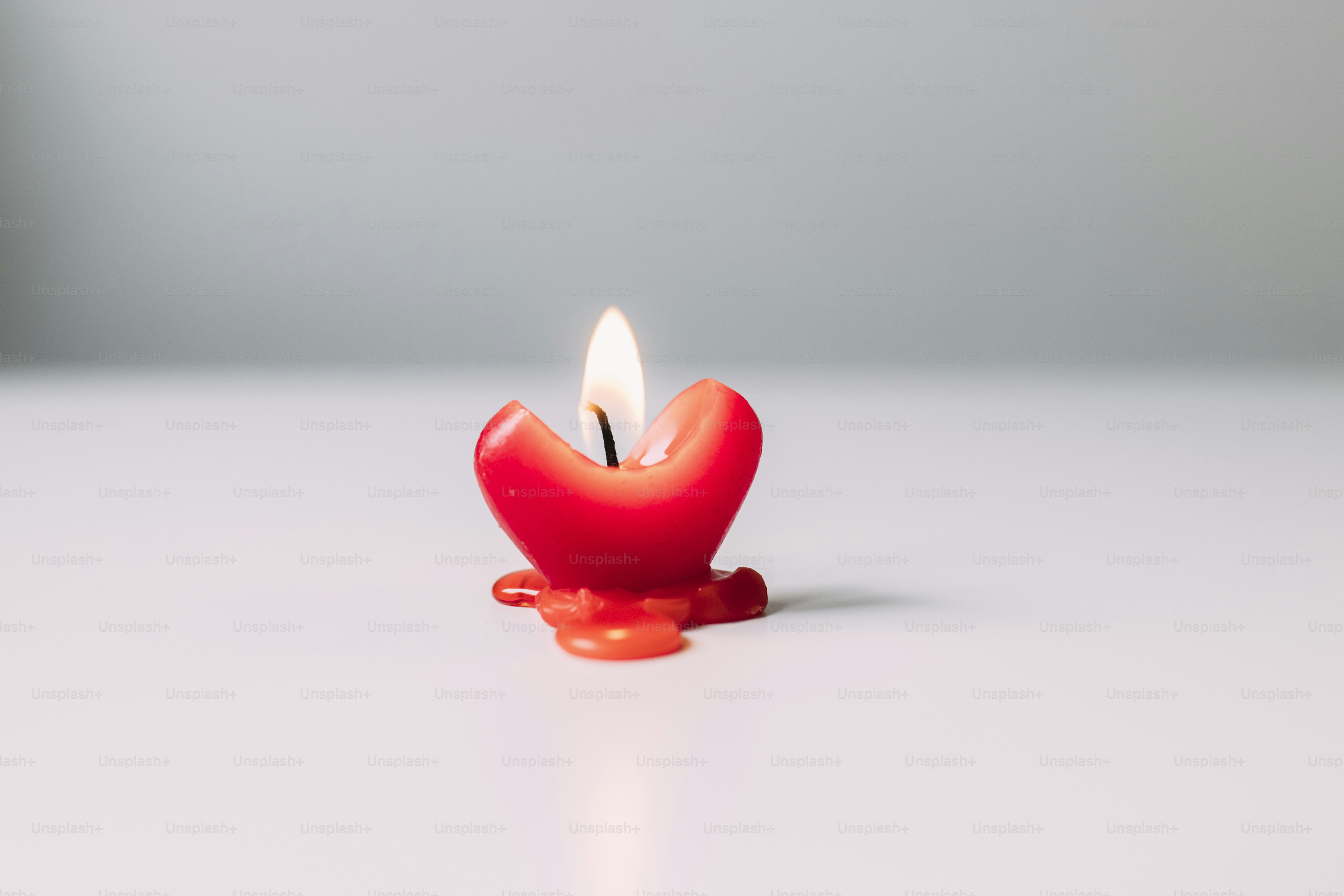白い表面に燃える赤いハート型のろうそく