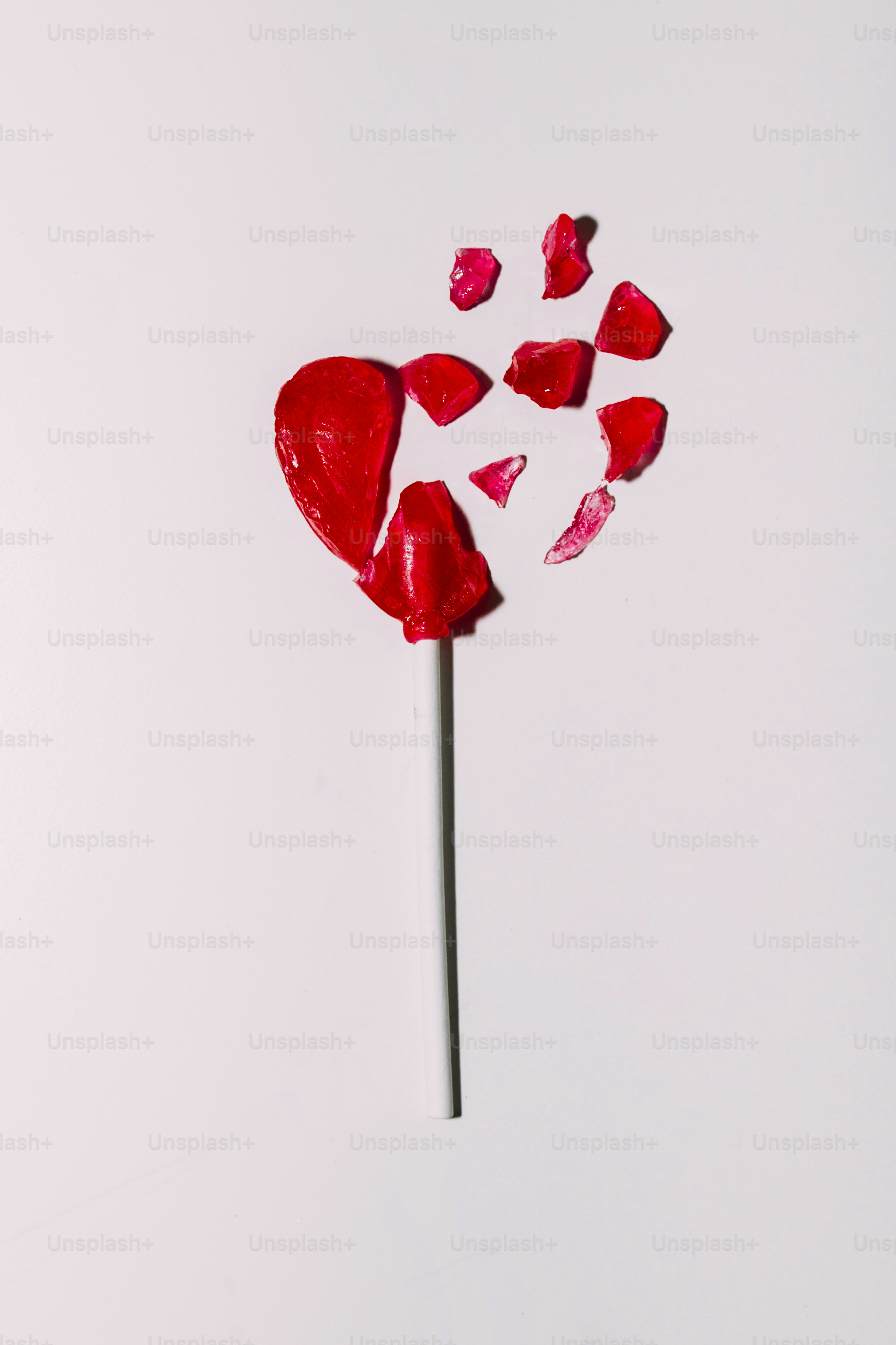 Broken heart-shaped lollipop on a stick.