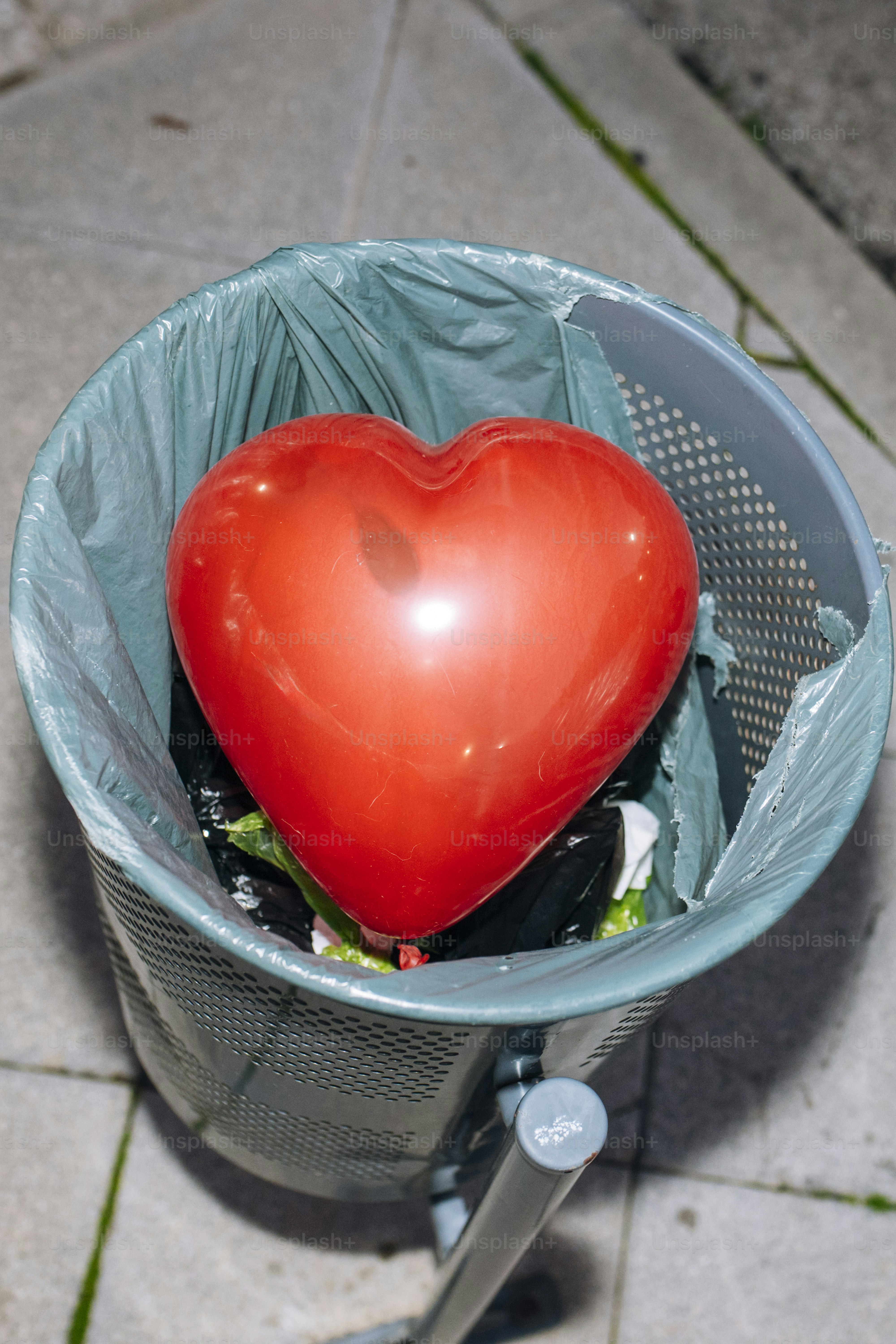 Palloncino a cuore rosso in un bidone della spazzatura