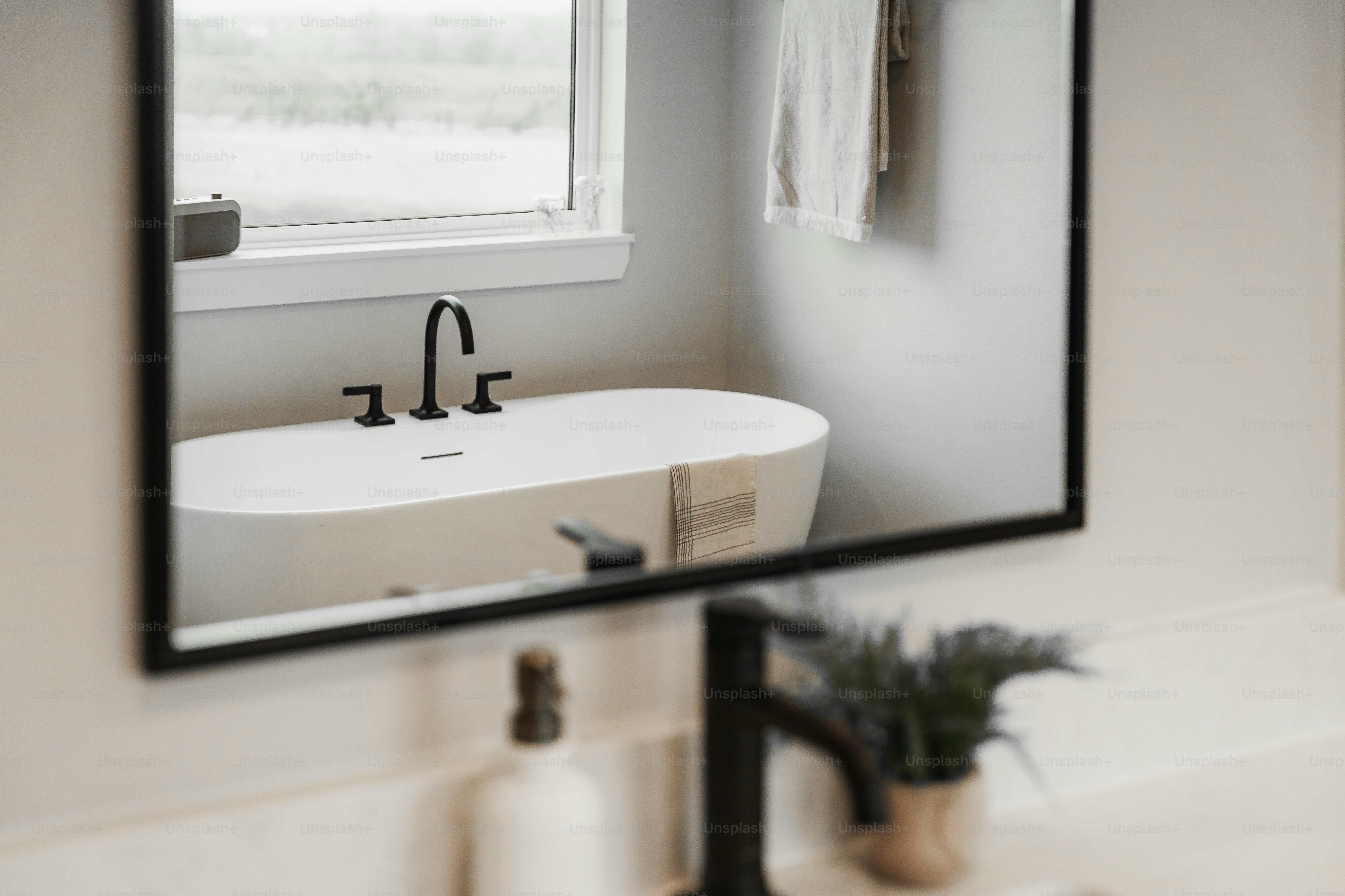 Modern bathroom with freestanding bathtub reflected in mirror.