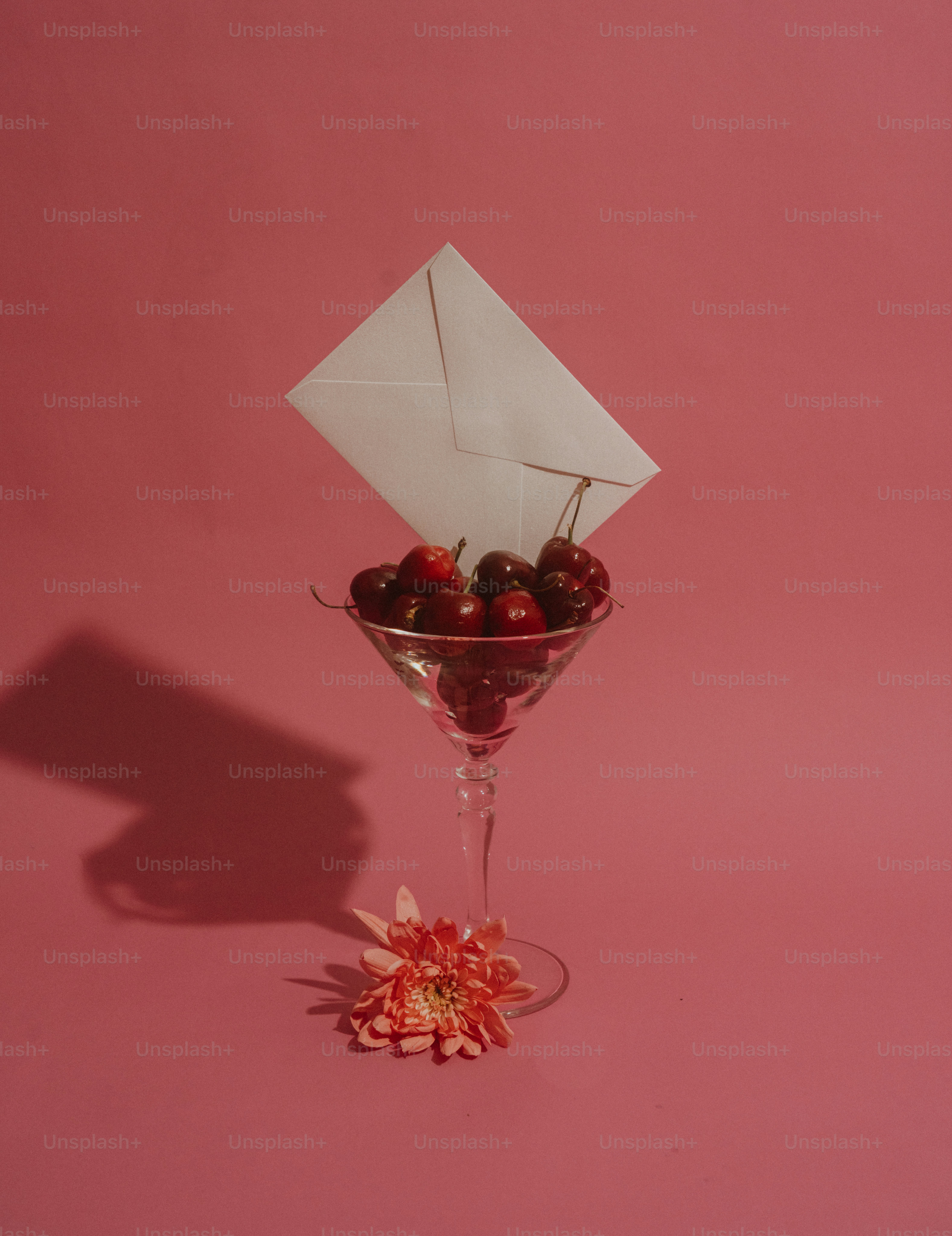 Kirschen im Martini-Glas mit Umschlag und Blume.