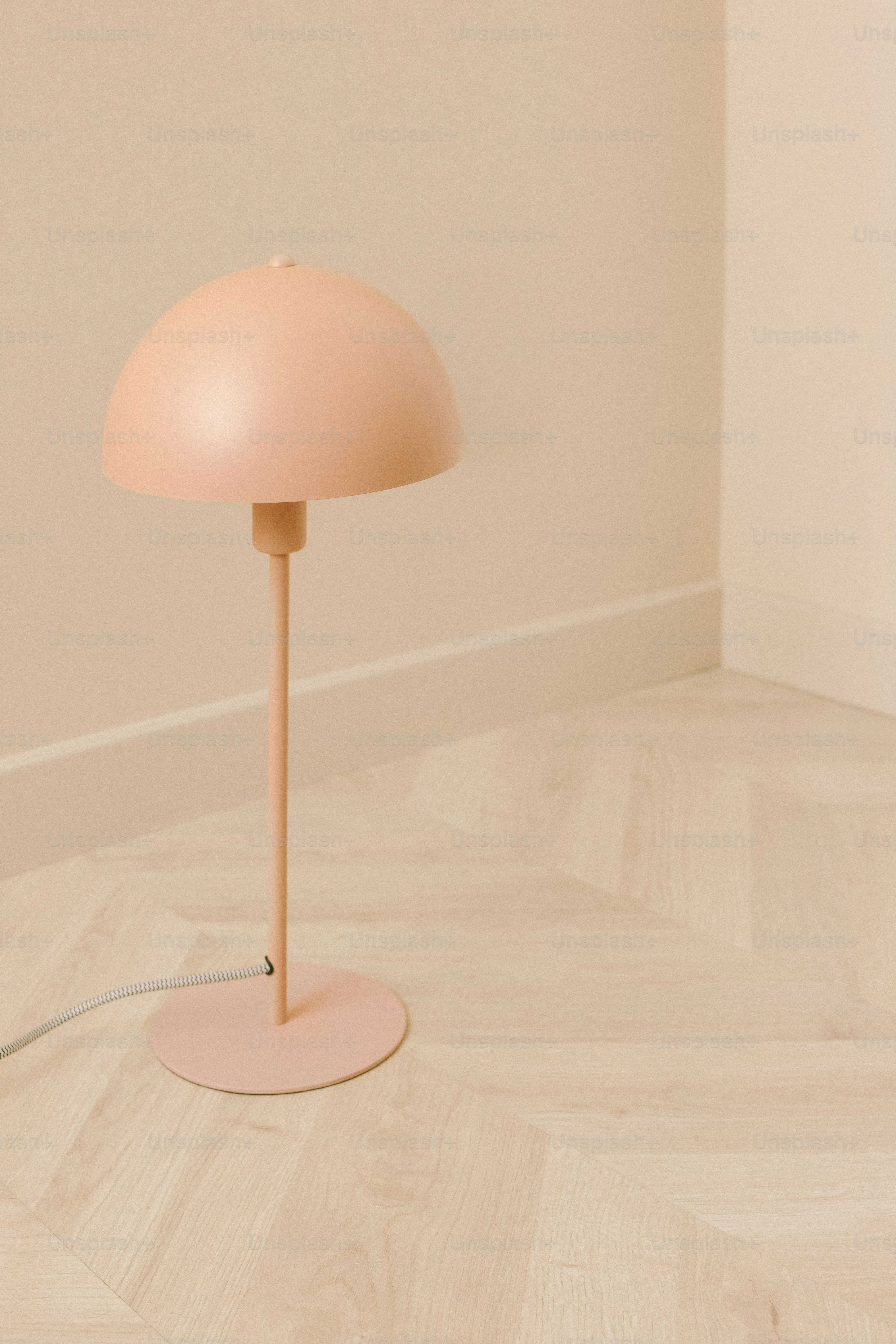 나무 바닥 위에 미니멀한 분홍색 테이블 램프.