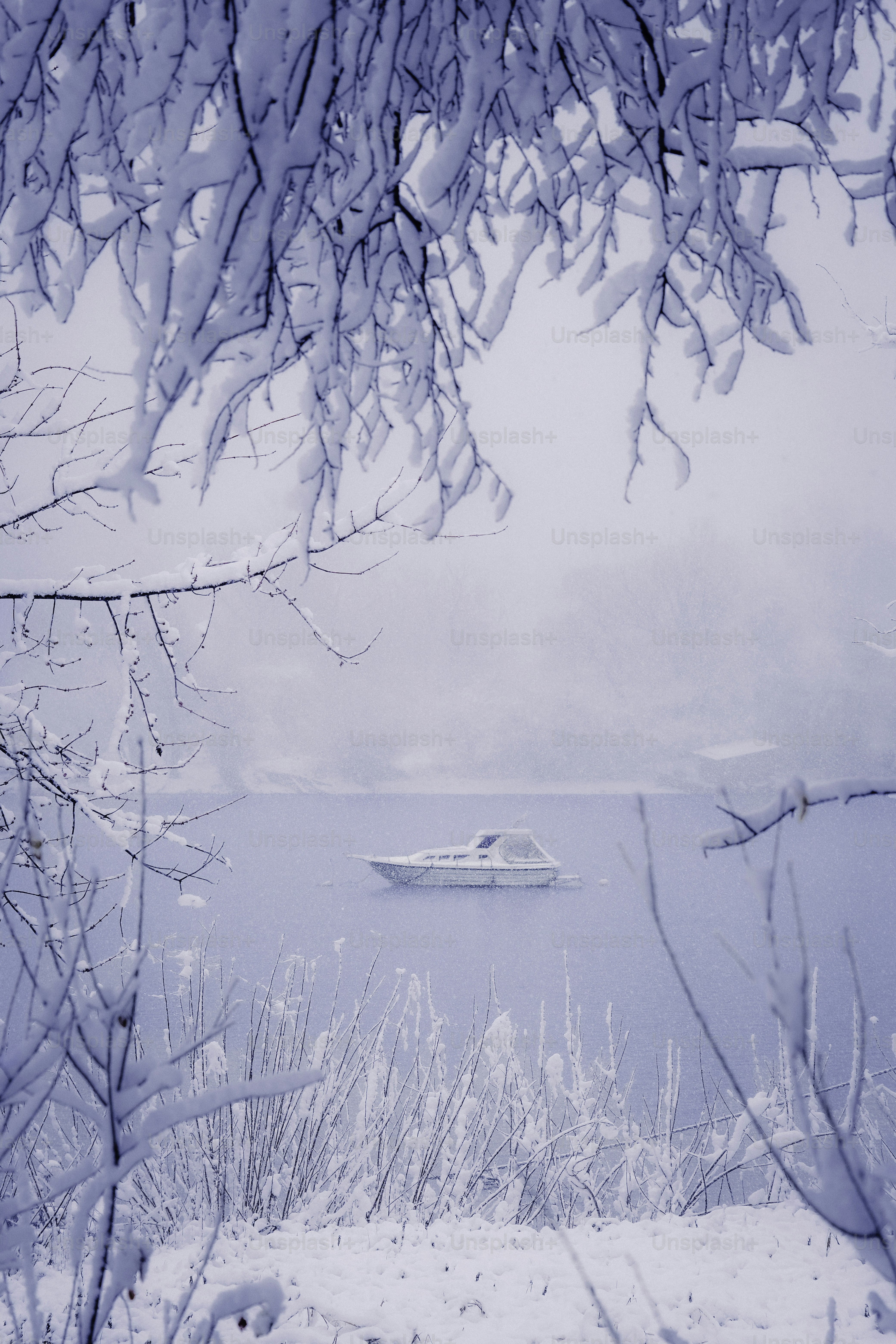 Ein einzelnes Boot treibt im Winter auf einem ruhigen See.